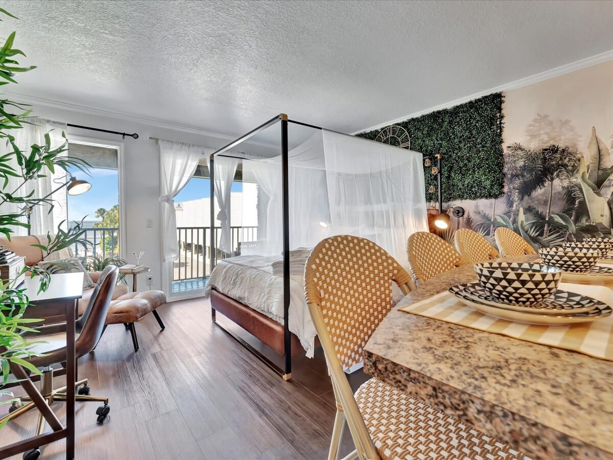 Drift into relaxation in your dreamy canopy bed, framed by botanical accents and an airy balcony that floods the room with natural light. Every detail invites you to unwind in style.