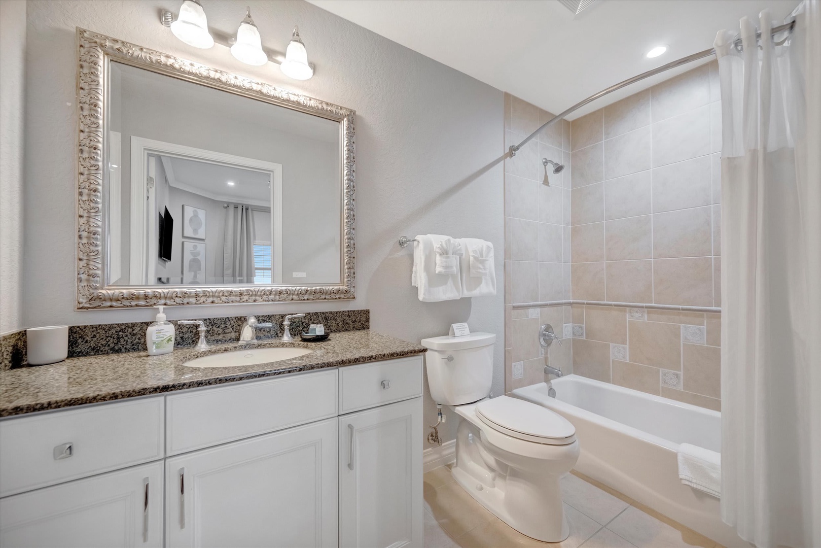 Step into your private bathroom featuring a spacious tub-shower combo and elegant granite countertops. Fresh towels await, and the bright vanity lighting ensures your mornings start refreshed and ready.