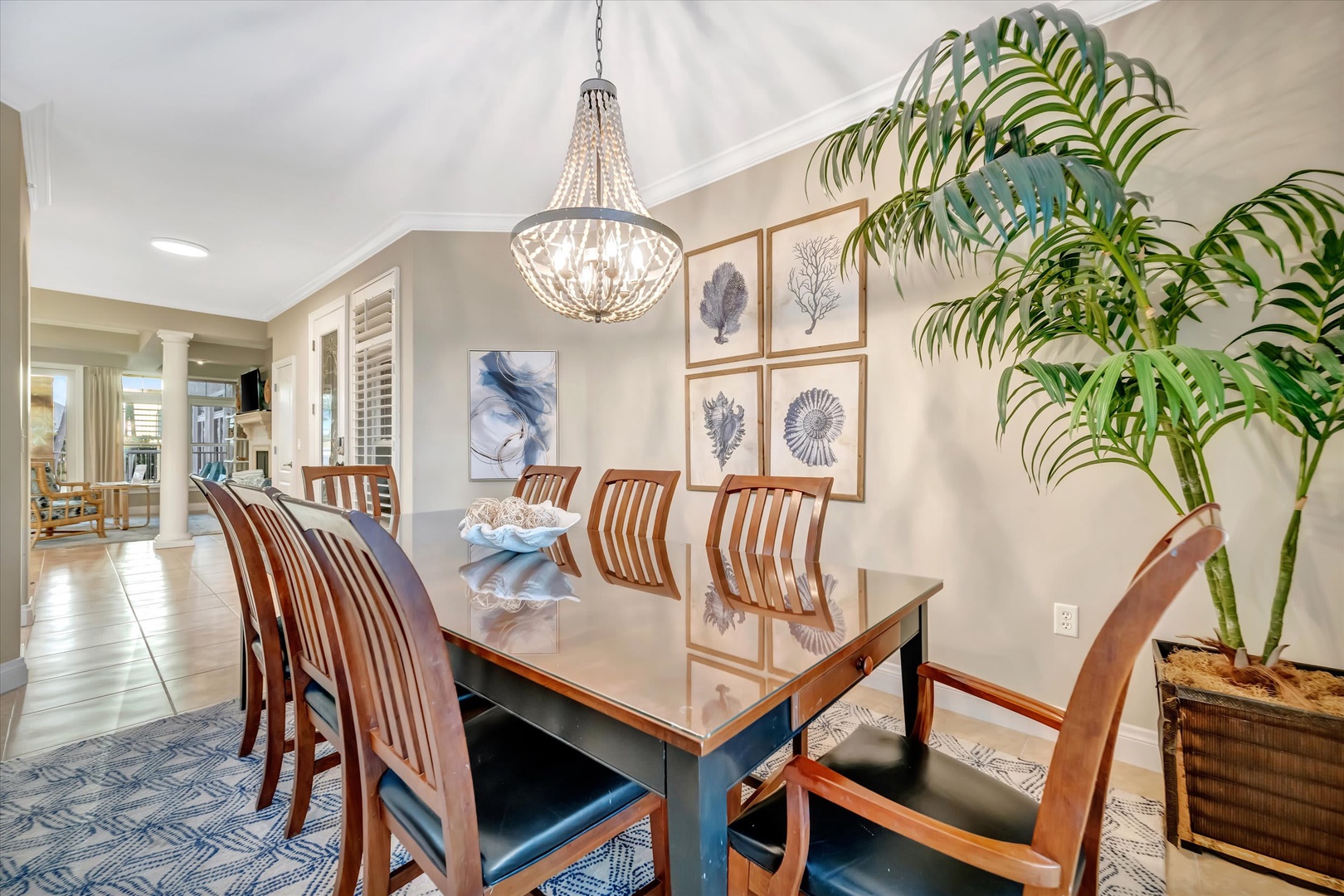 Gather around this elegant dining table, where coastal-inspired art and a sparkling chandelier set the tone for memorable meals together.