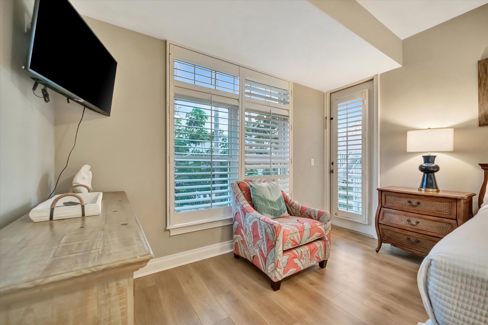 Settle into your cozy reading chair by plantation shutters that frame natural light and garden views. Your private retreat includes a mounted TV and bedside storage for all your comforts.