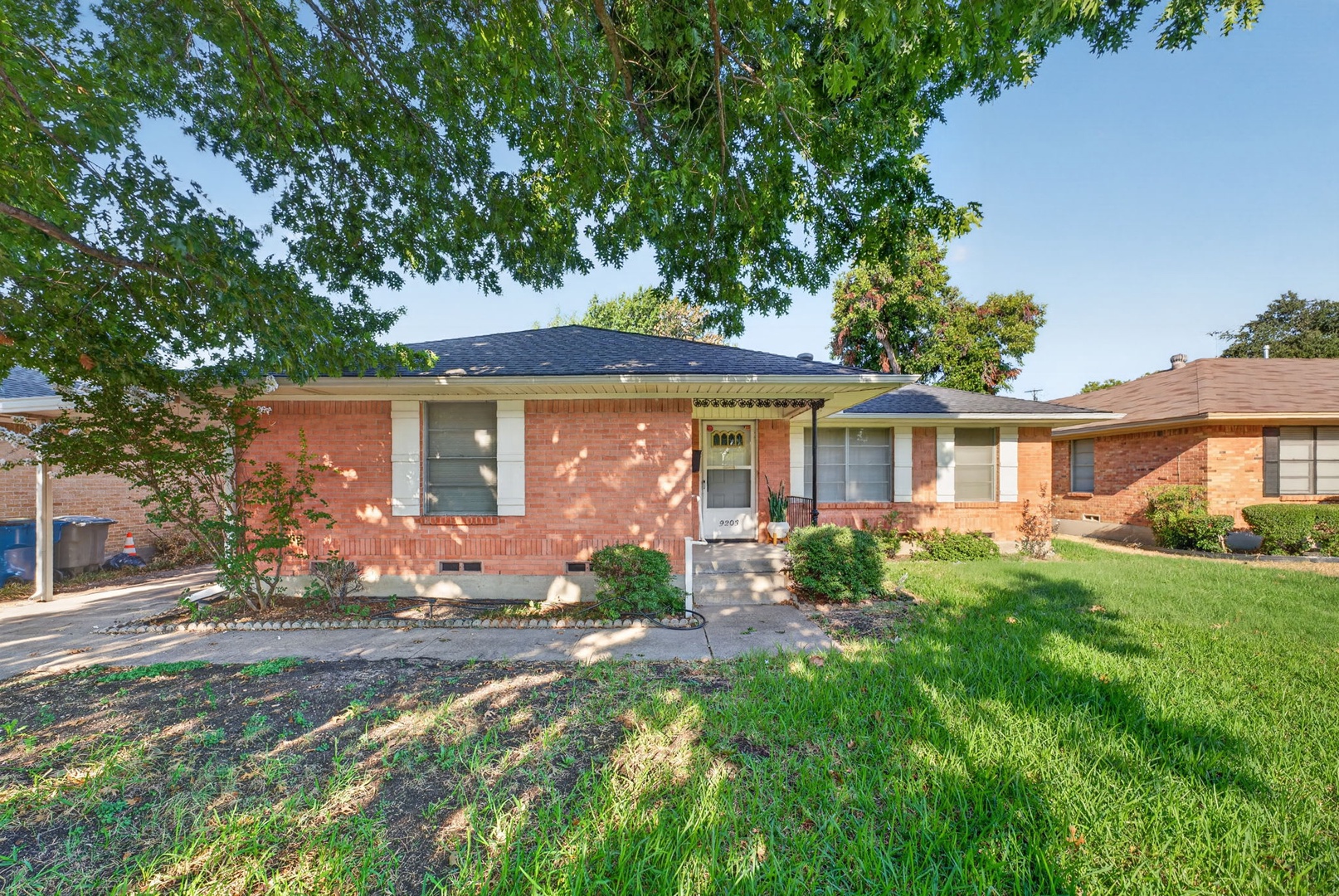 A charming brick home set in a quiet residential neighborhood, surrounded by mature trees and well-maintained landscaping—a welcoming retreat for your getaway.