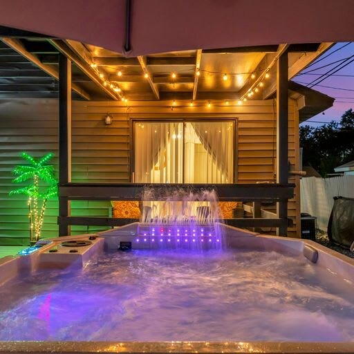 Soak under the stars in your private hot tub, glowing with vibrant lights and surrounded by warm string lighting overhead. A perfect retreat after exploring the area.