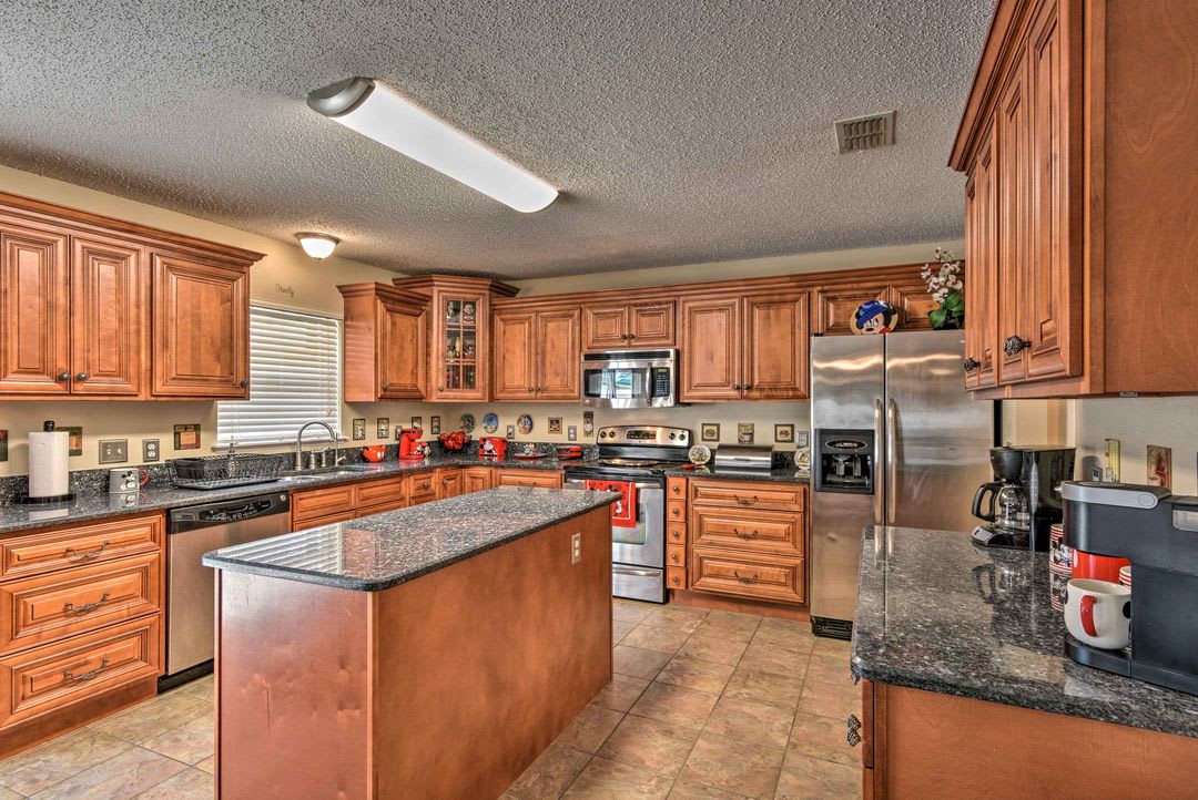 Prepare your favorite meals in this spacious kitchen, featuring rich wood cabinetry, granite countertops, stainless steel appliances, and plenty of workspace on the central island for all your culinary adventures.