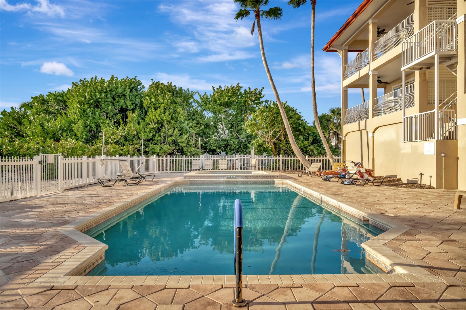 Crystal-clear waters invite you to unwind beside swaying palms and lush tropical greenery, where sunbeds await your leisurely afternoons under sunny skies.