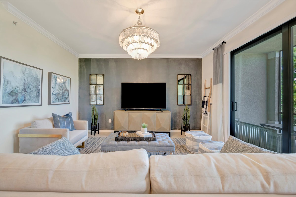 Sink into plush seating beneath a stunning chandelier. The neutral palette and natural textures create a serene gathering space where you can unwind in style.