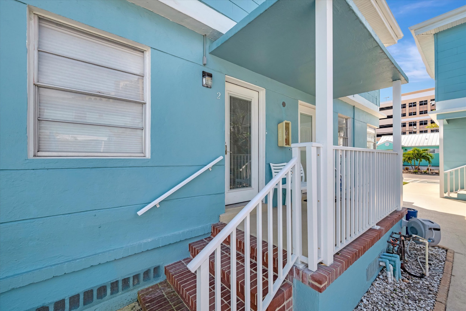 Charming turquoise cottage entrance welcomes you to your beachside retreat, where coastal living meets cozy comfort under sunny skies.