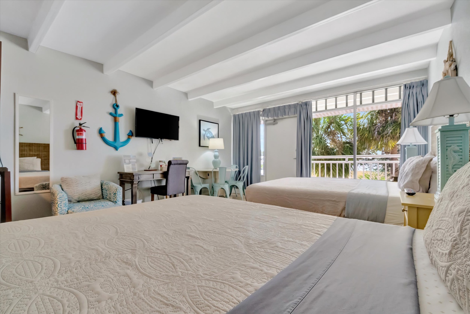 Rest easy in this coastal-inspired bedroom with two cozy beds and cheerful nautical touches. Step onto your private balcony and soak in the lush palm views that set the scene for your tropical escape.