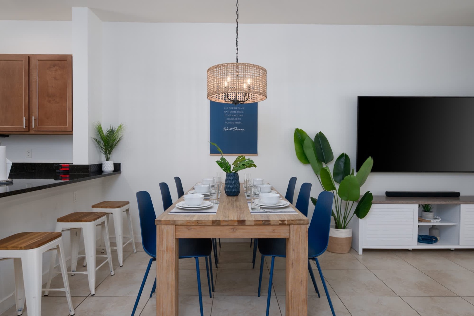 Warm wood tones and coastal-inspired blue accents create an inviting dining area that flows seamlessly into the kitchen, perfect for leisurely meals and good conversation.
