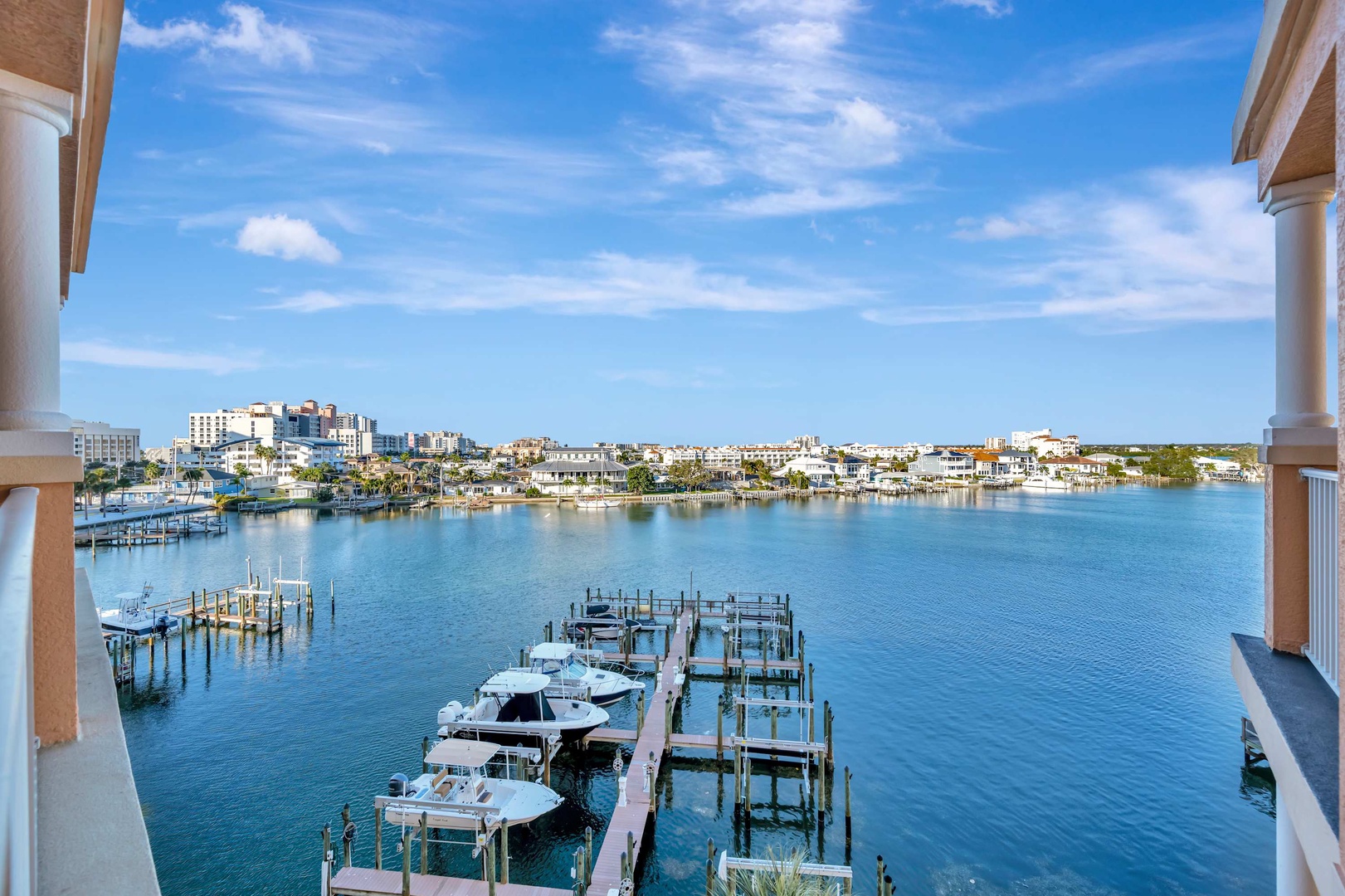 Picture your morning coffee on this balcony, gazing across calm marina waters toward coastal homes and city buildings beyond. The clear skies and serene blue invite you to settle in and simply breathe.