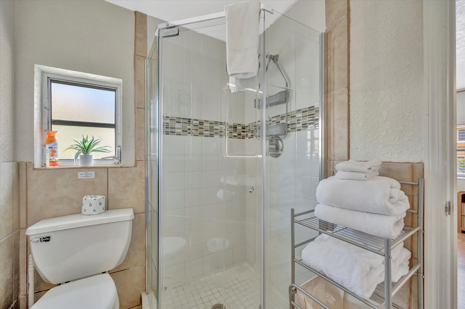 Step into your refreshed bathroom with a spacious walk-in shower, crisp tile work, and fluffy towels ready for you after a long day of exploring.