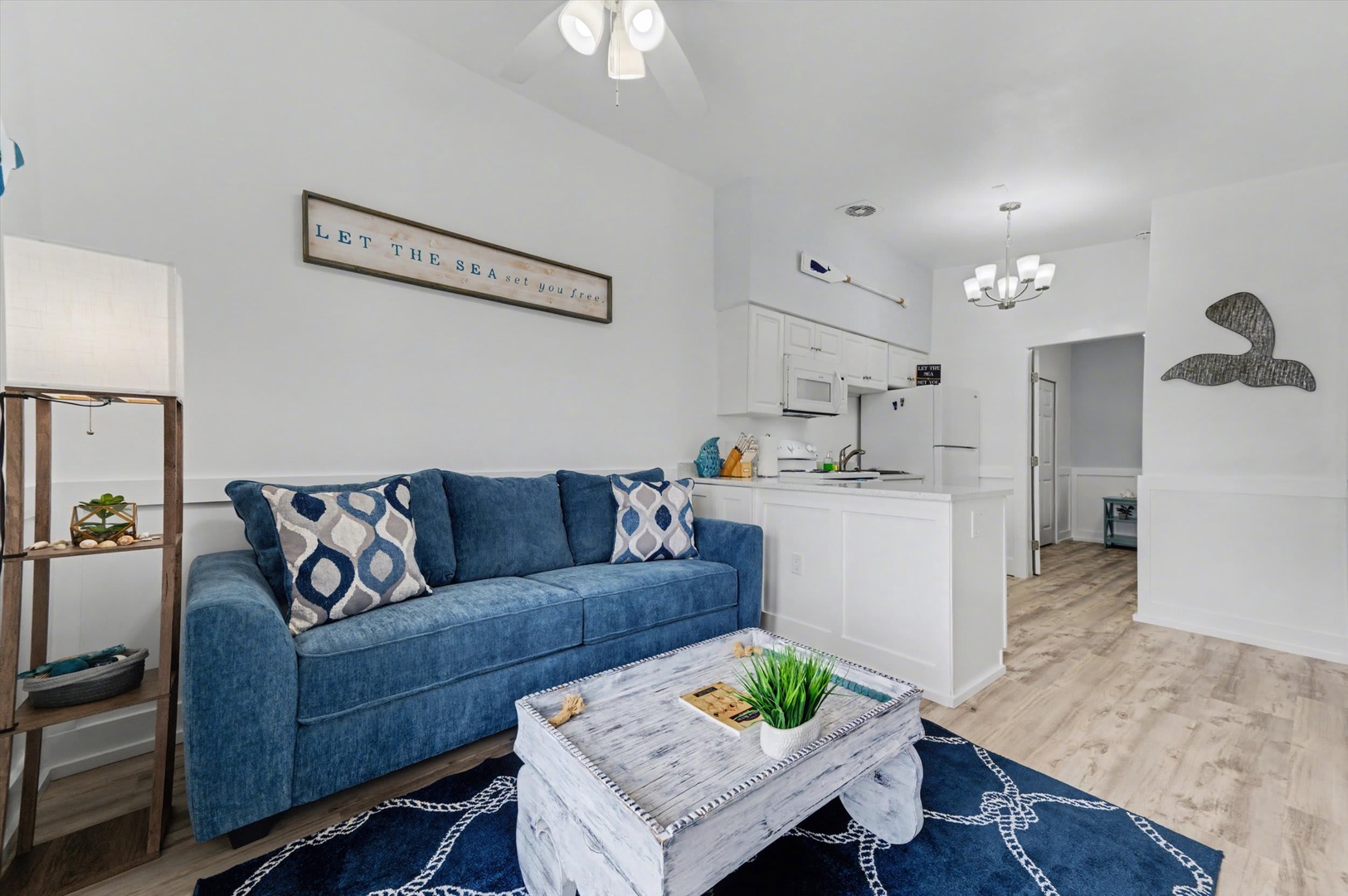 Sink into the plush blue sofa and let the coastal vibes wash over you. Your open-concept living space flows seamlessly into a fully-equipped kitchen, perfect for leisurely mornings and breezy evenings.