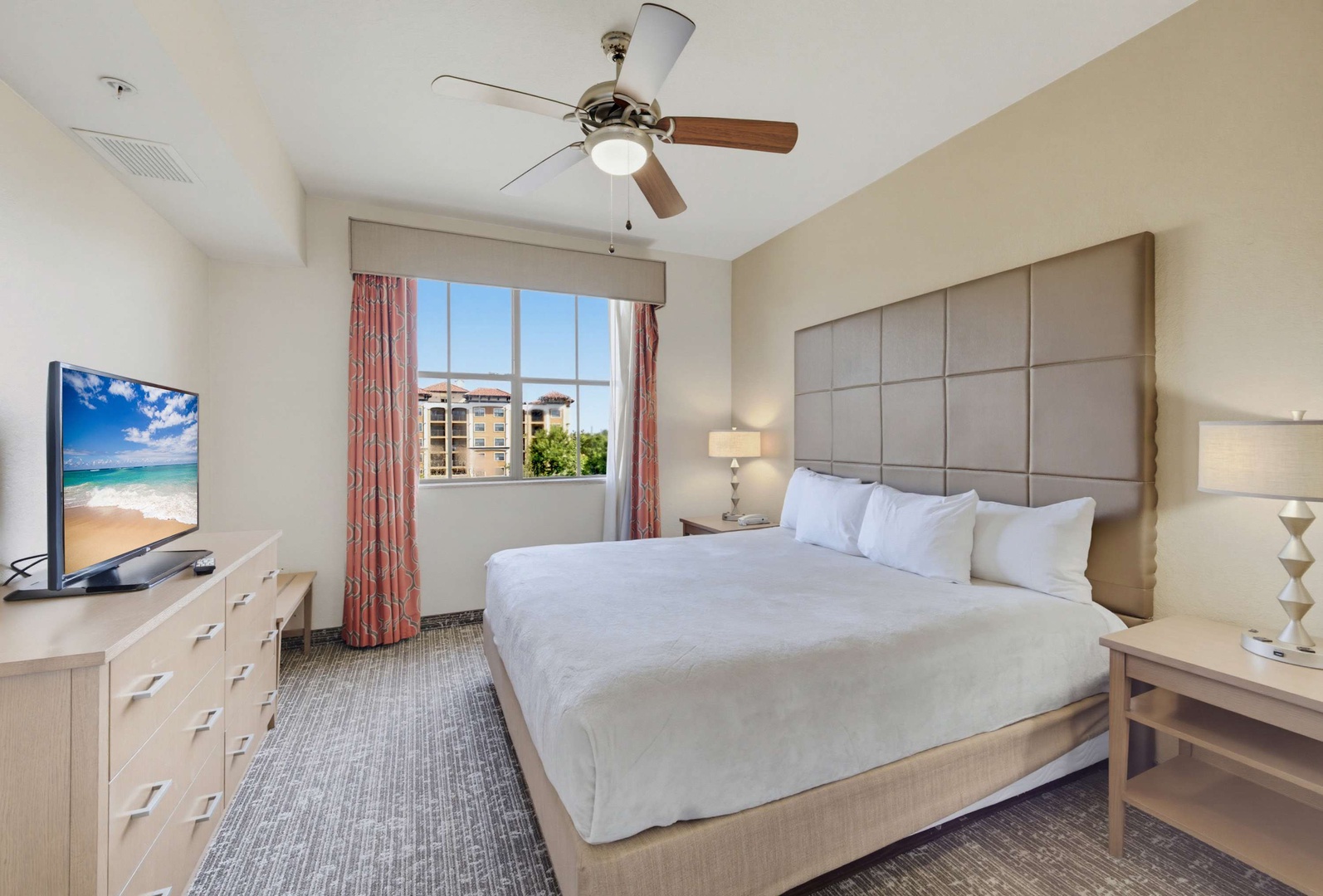 Slip between crisp white linens and drift off beneath the gentle whirl of the ceiling fan. Your comfortable retreat features modern furnishings, soft lighting, and everything you need for a peaceful night's rest.