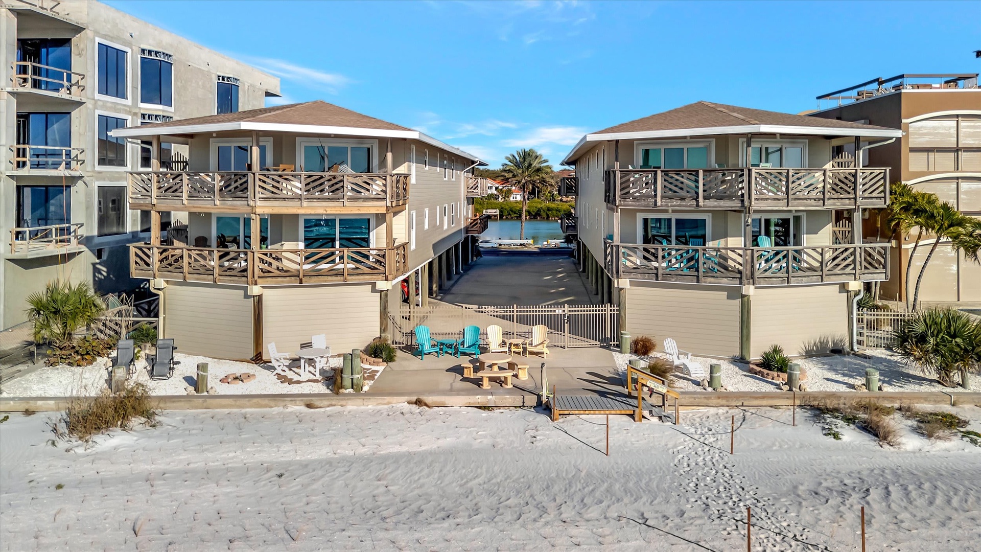 Beachfront vacation rental featuring direct sandy beach access, multiple balconies overlooking the water, and private outdoor seating areas with fire pit.