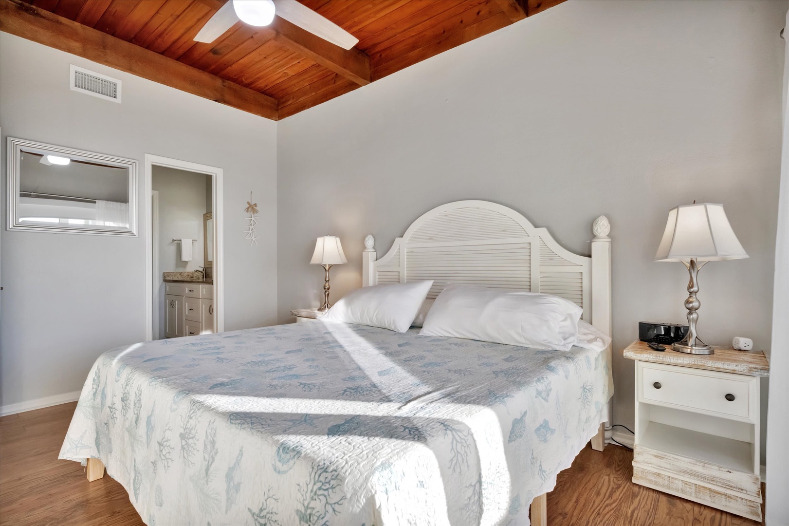 Sink into crisp linens beneath vaulted wood ceilings that add warmth and charm to your coastal retreat. Soft lighting and beachy accents create a serene sanctuary for restful nights.