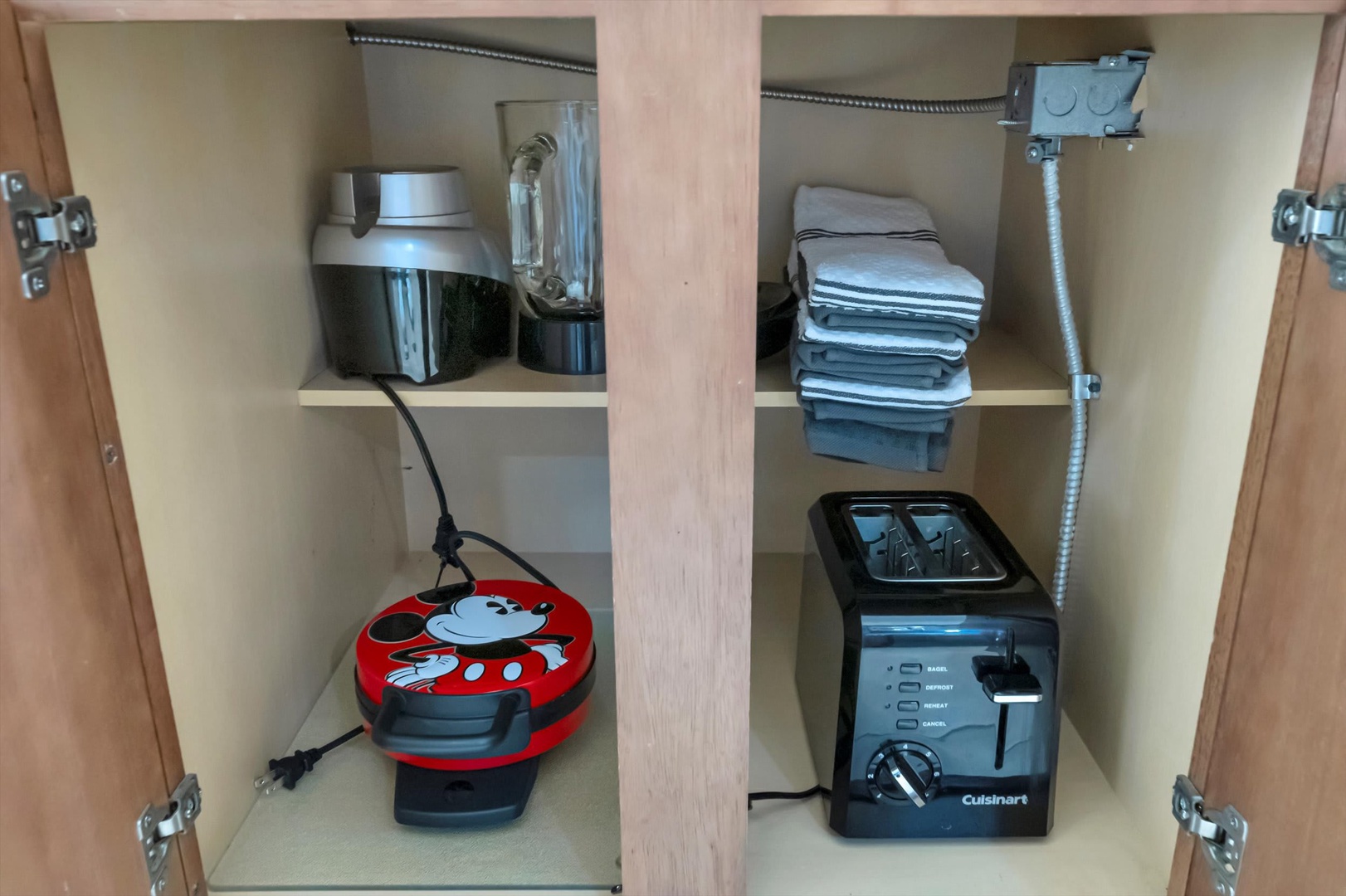 Your kitchen comes fully stocked with essentials—neatly folded dish towels, a coffee maker, toaster, and even a playful waffle maker ready for lazy morning breakfasts.
