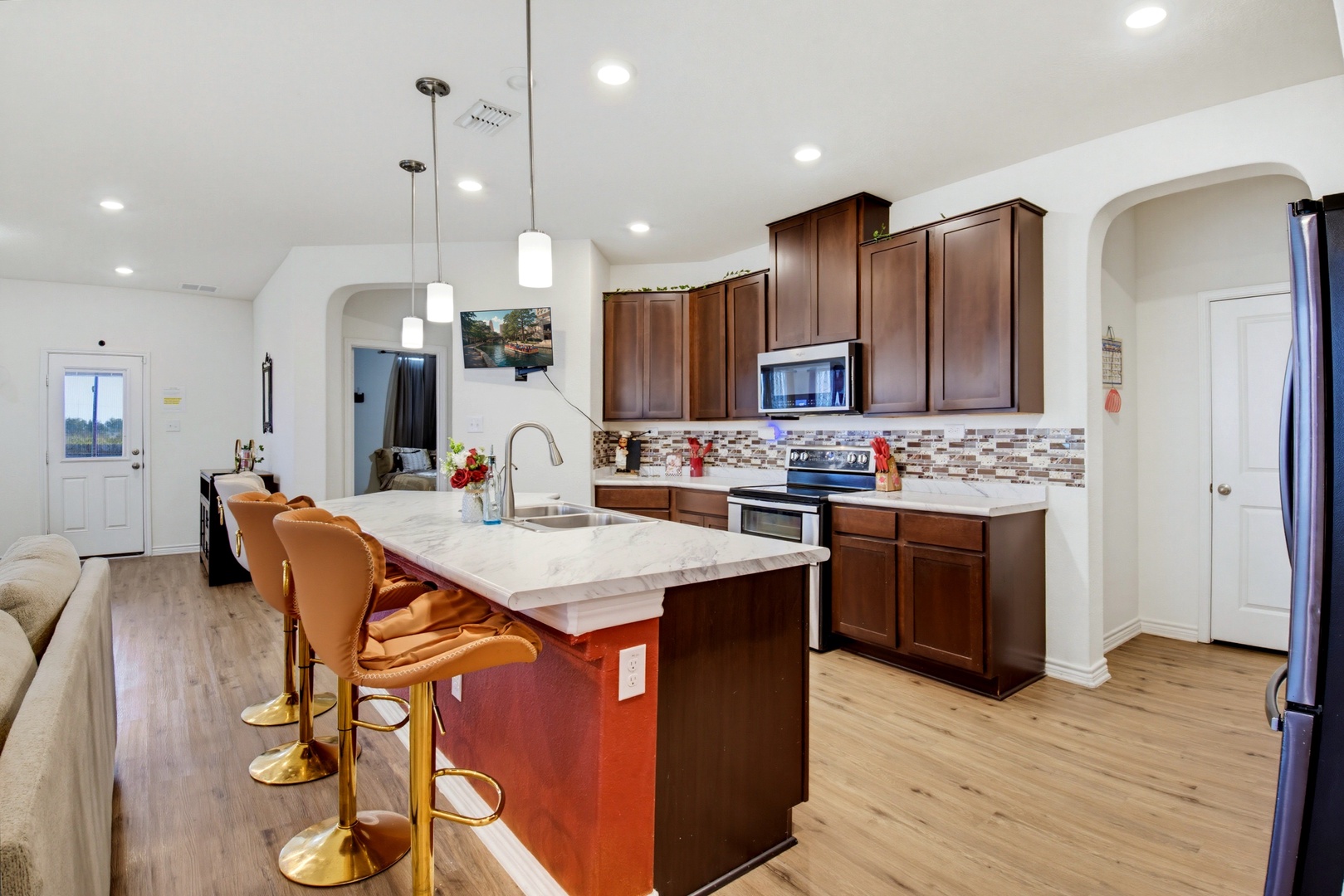 Step into your gleaming kitchen with warm wood cabinetry, marble-topped island, and modern appliances ready for your culinary adventures.