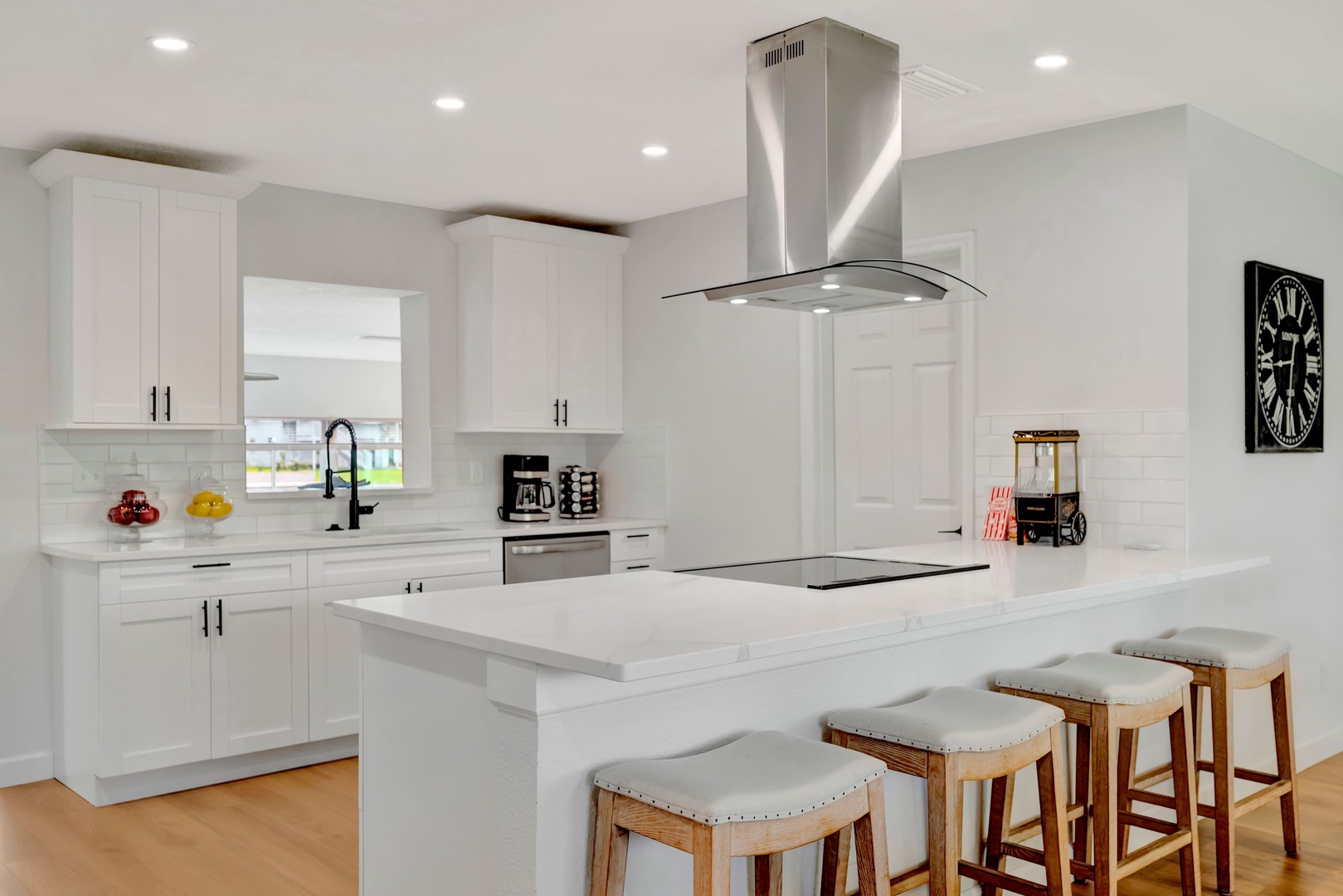 A pristine, modern kitchen awaits with sleek white cabinetry, marble countertops, and a spacious island where you can gather for morning coffee or prepare your favorite meals together.