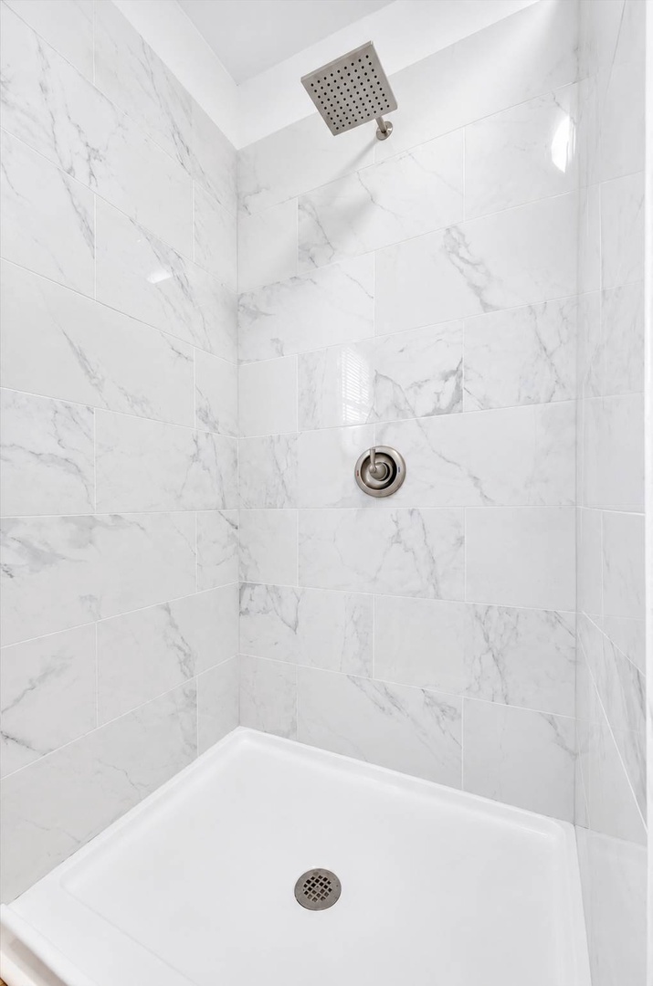 Slip into a spa-like escape with sleek marble-effect tiles, a modern rainfall showerhead, and spotless white surfaces that make your morning refresh feel luxurious.