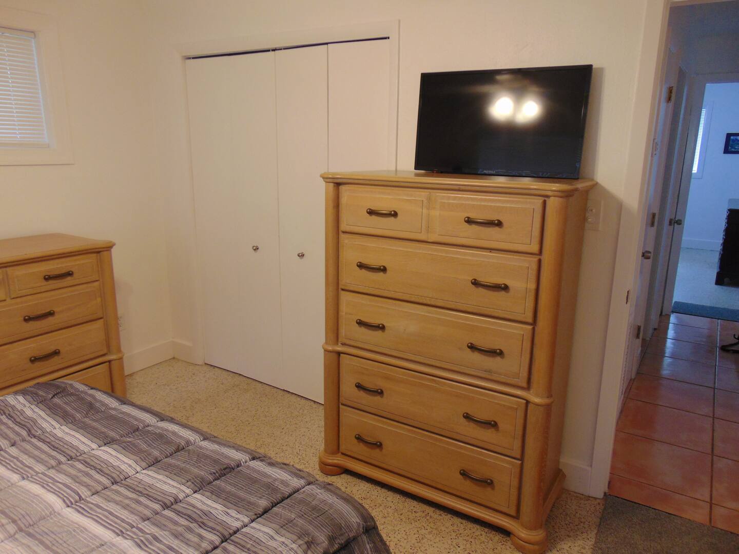 Your bedroom offers comfortable simplicity with warm wood furnishings, plenty of storage in the dresser and closet, and a mounted TV for unwinding after your day of exploring.