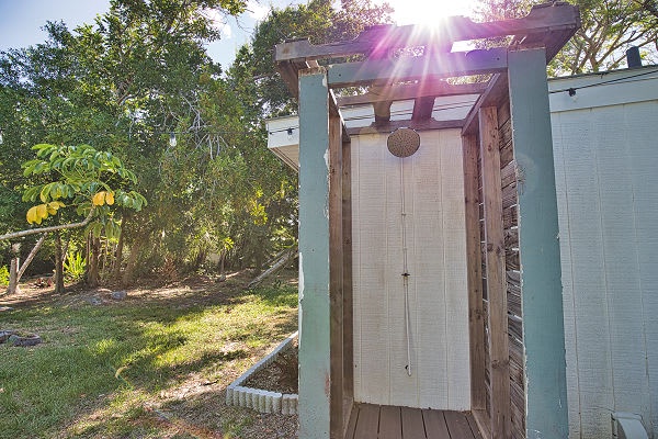 Step into your private outdoor shower, surrounded by lush greenery and warm sunlight filtering through the trees—a refreshing open-air escape after a day of adventure.