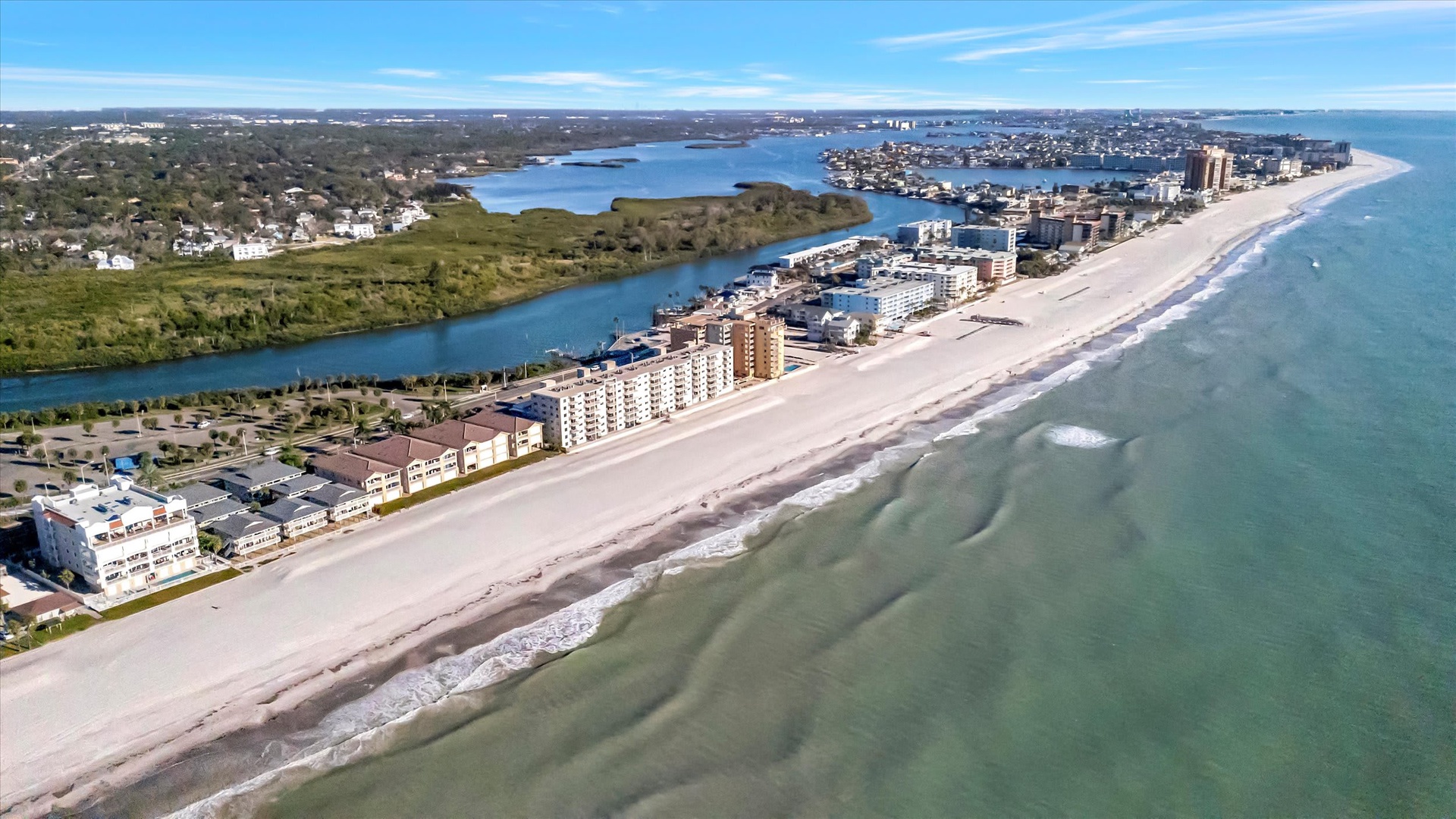 Aerial view of the beachfront property location, showcasing the pristine sandy shore, coastal development, and surrounding waterways defining the area.