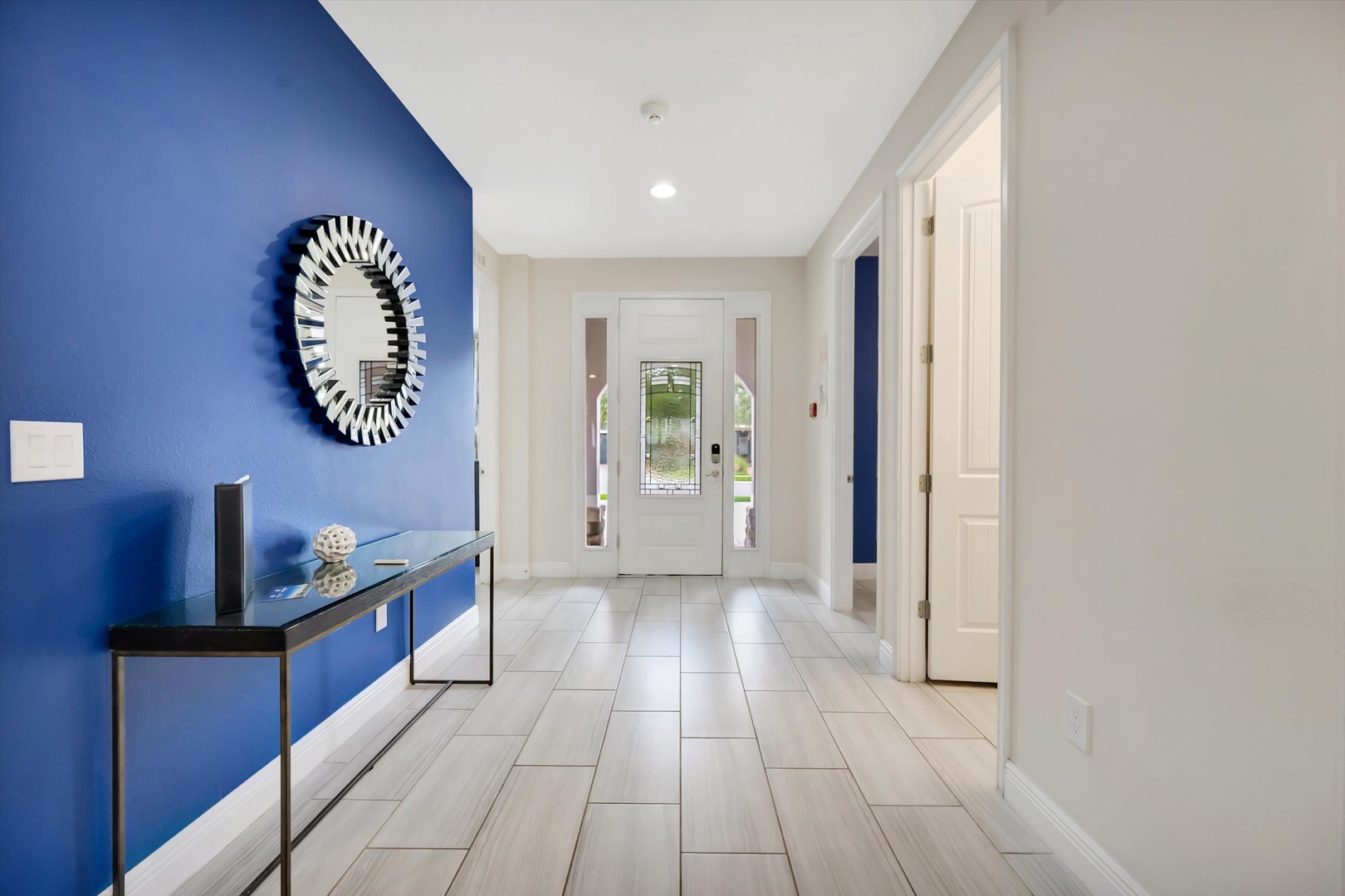 Step into a bright, welcoming entryway with a striking blue accent wall and elegant wood-look tile floors that guide you through the home.
