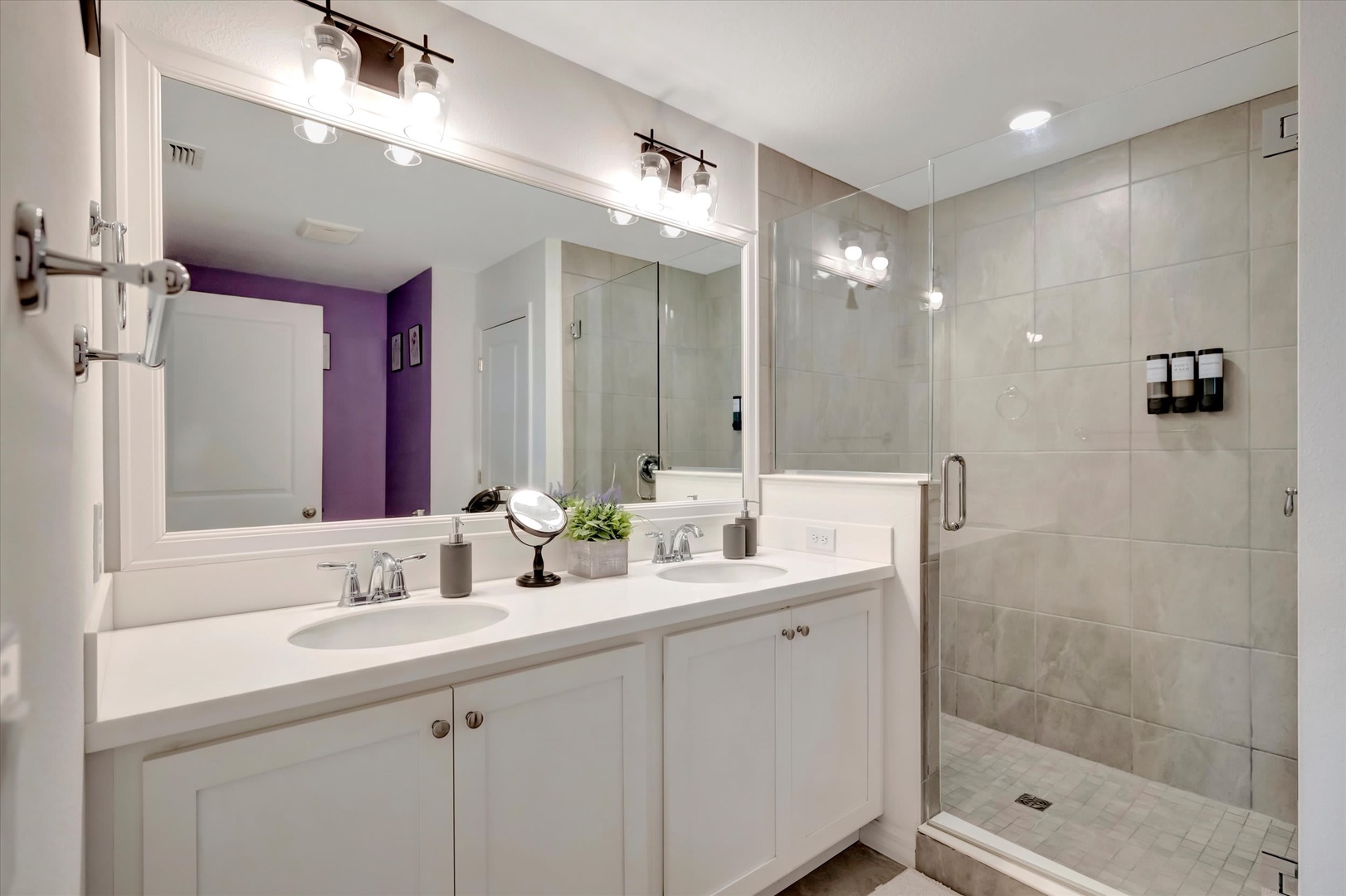 Refresh in your modern bathroom with dual sinks, ample counter space, and a spacious walk-in shower with elegant tiling and glass enclosure.