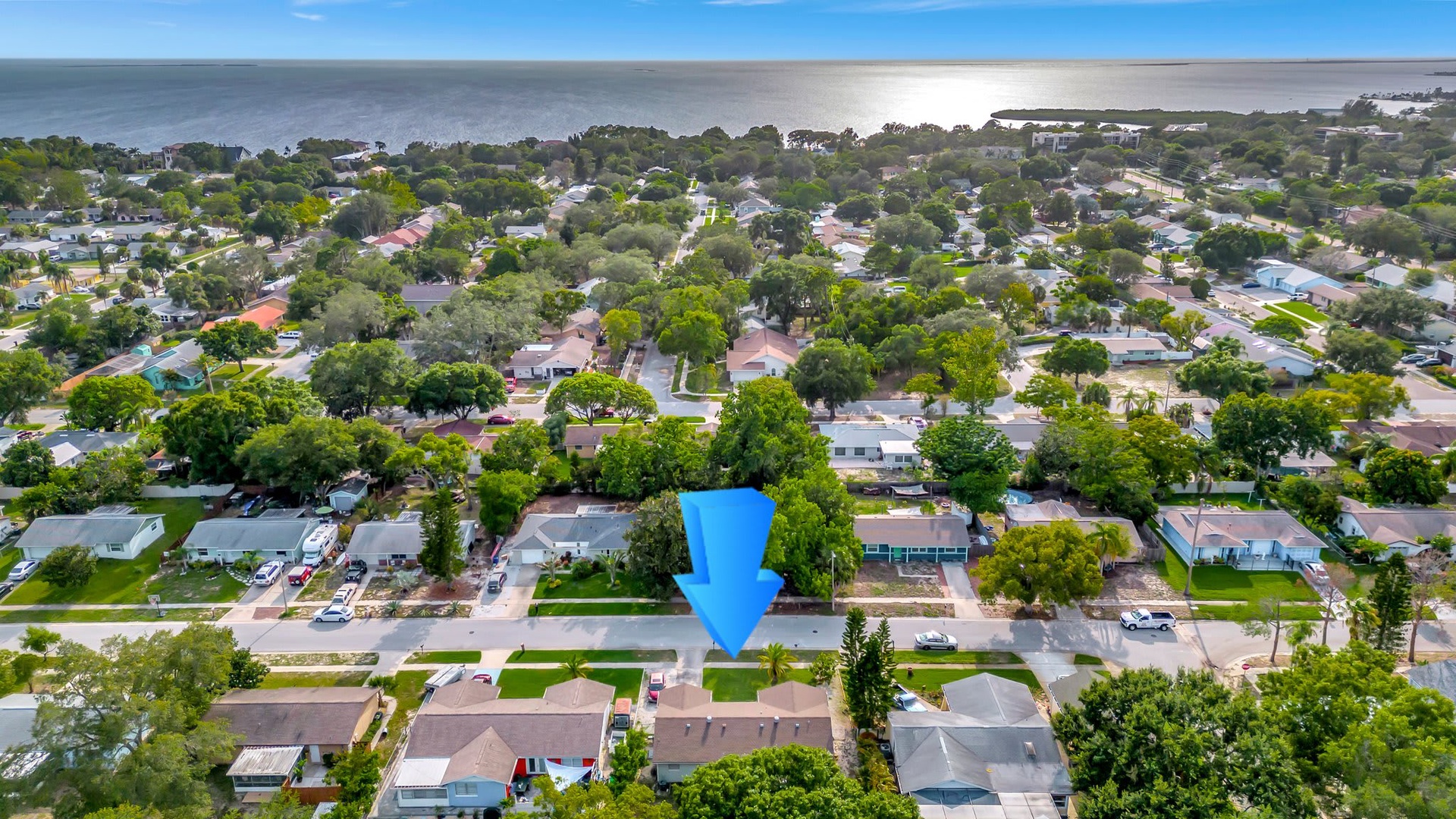 Aerial view of a charming coastal neighborhood nestled among lush greenery, with tranquil waters visible in the distance.