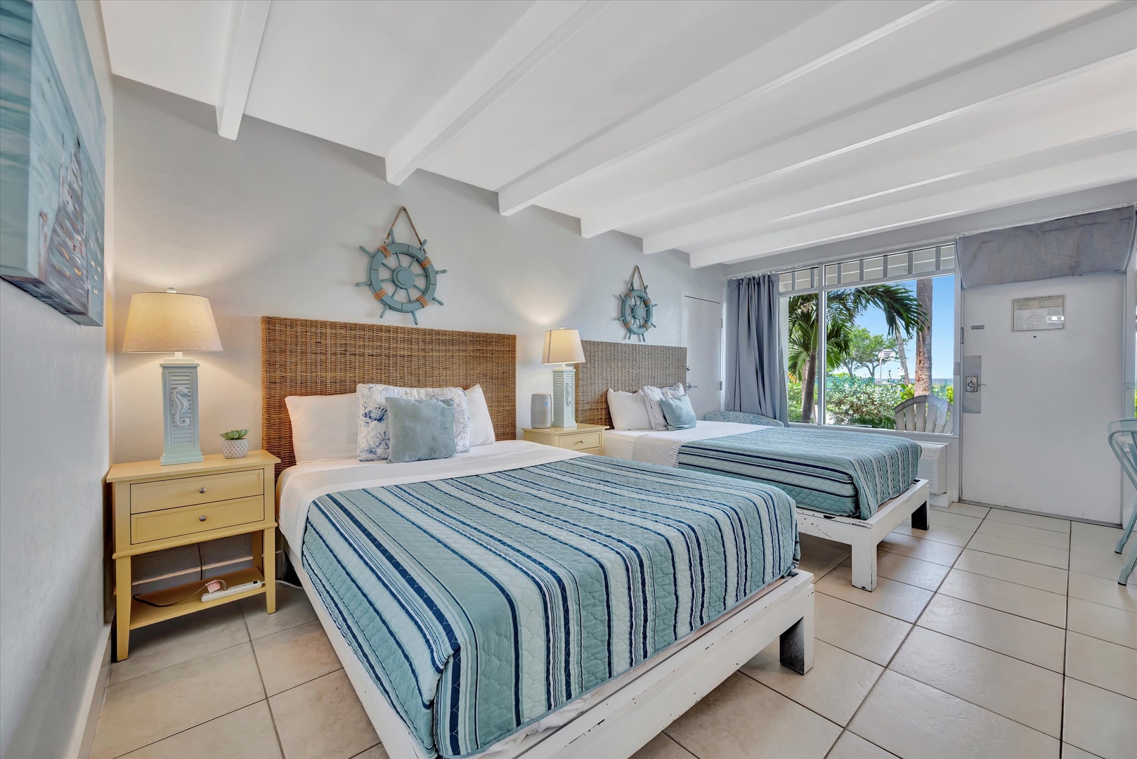 Sink into coastal calm with two plush beds dressed in breezy blues and crisp whites. Wake to palm trees swaying just beyond your window and drift off under charming nautical touches.