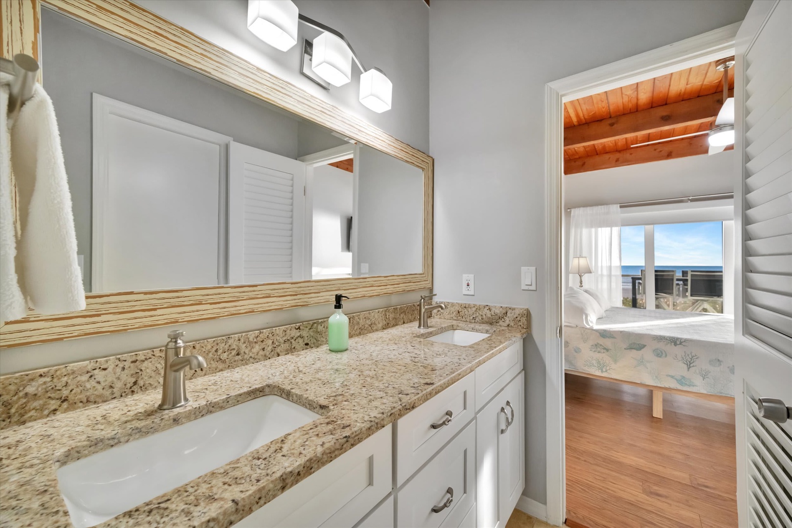 Freshen up in your light-filled bathroom with granite counters and elegant fixtures. Through the doorway, catch a glimpse of the sea view that awaits you just steps away.