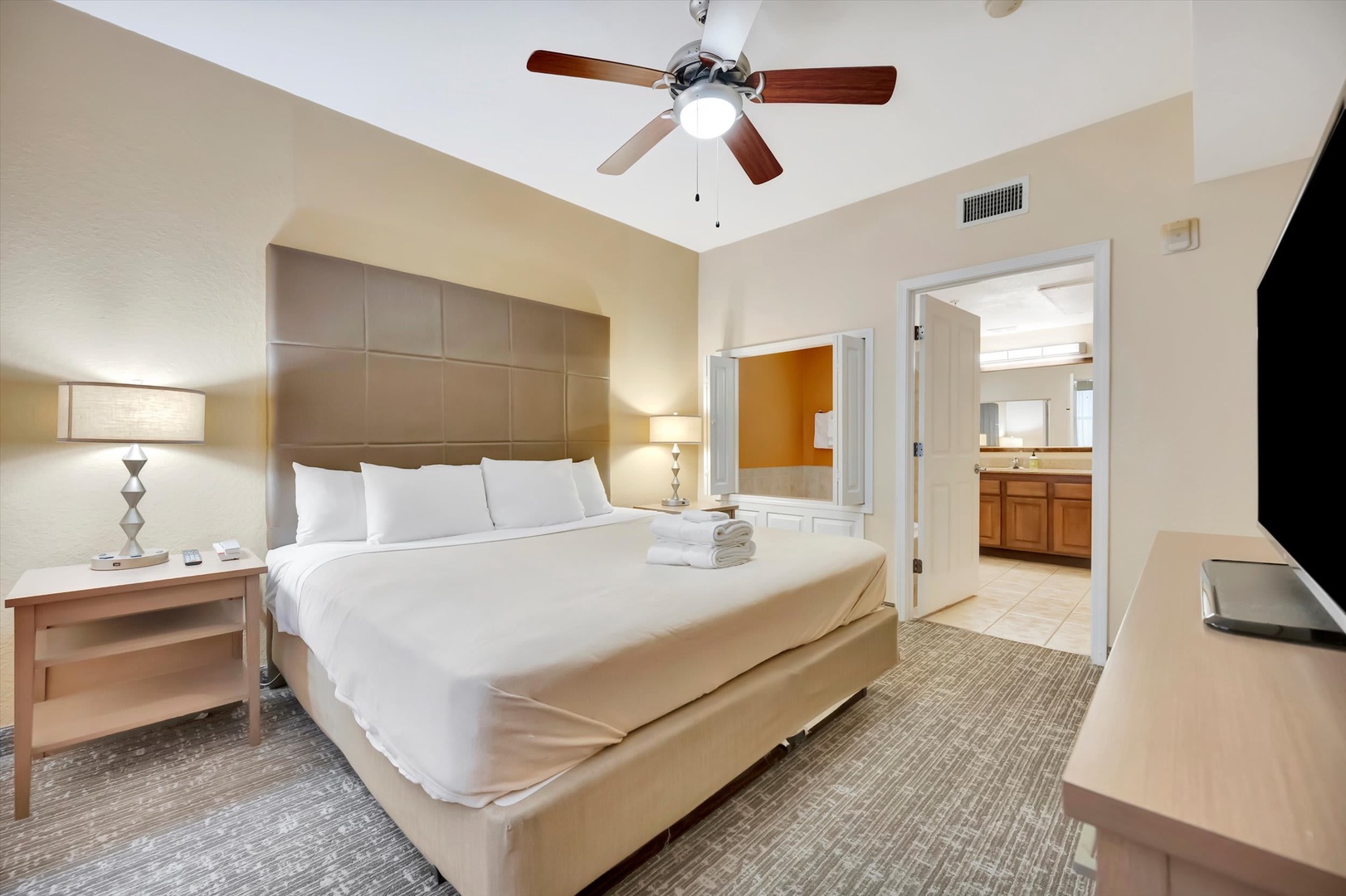 Slip into crisp linens beneath a vaulted ceiling with a gentle ceiling fan above. Your ensuite bathroom awaits through the adjoining door, and fresh towels are ready for you.