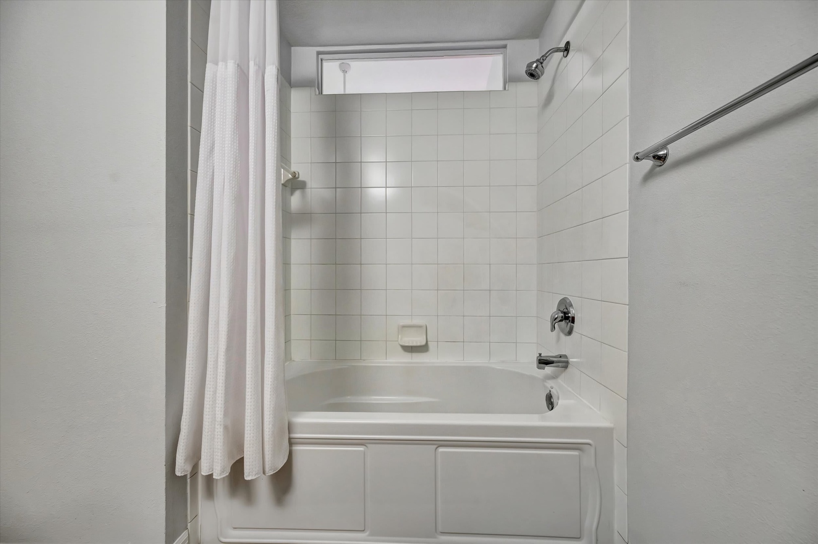 Step into your clean, bright bathroom with a full-size tub-shower combo. Fresh white tiles and a spacious design make it easy to unwind after a day of exploring.