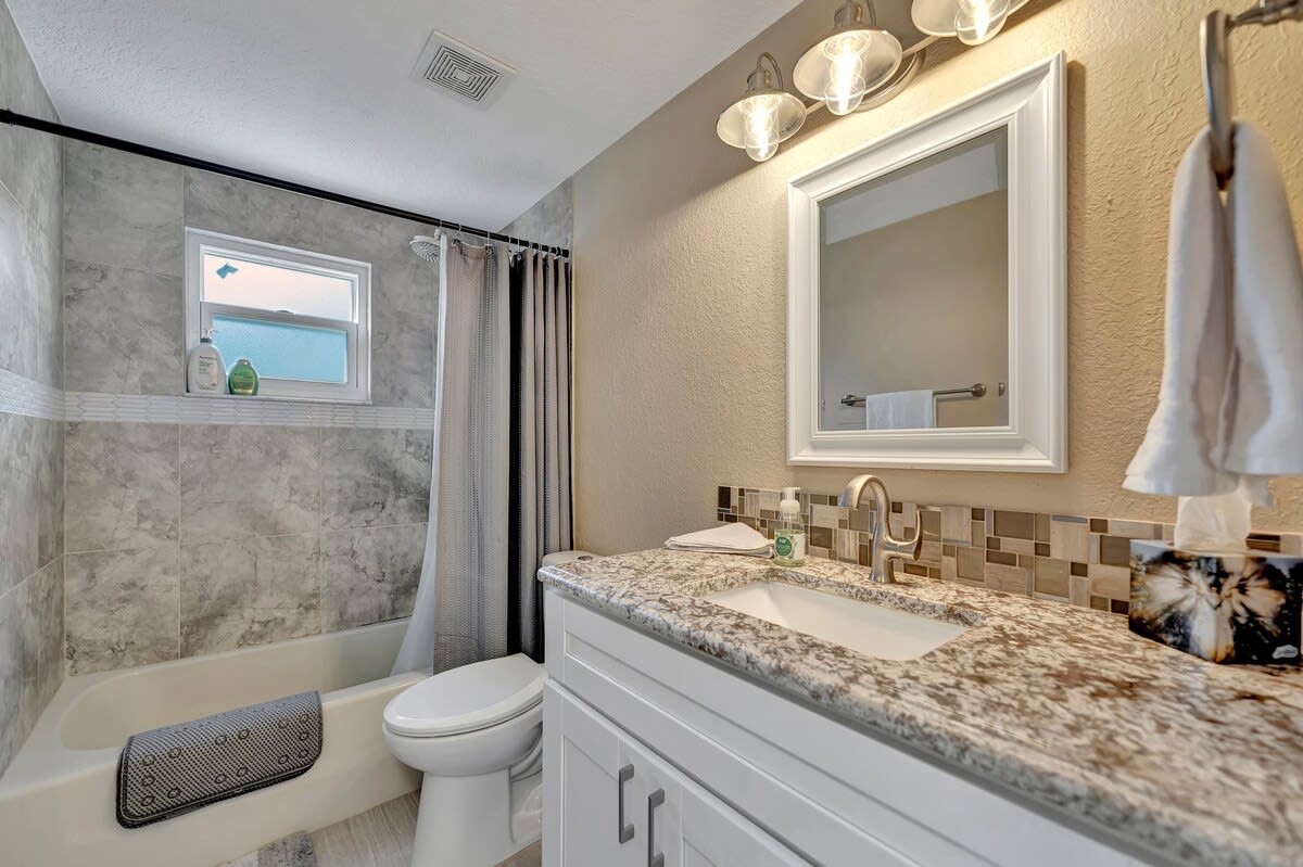 Step into your beautifully updated bathroom, where gleaming granite counters and warm lighting set a welcoming tone. Soak in the tub-shower combo surrounded by soft gray tile, and enjoy the thoughtful touches like fresh towels and a framed mirror.