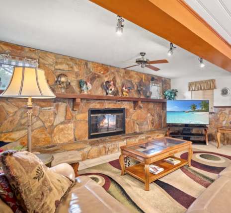 /ഛ//step/Youഛ'll love relaxing in this spacious living room, where a stunning stone fireplace anchors the space and beamed ceilings add rustic charm.