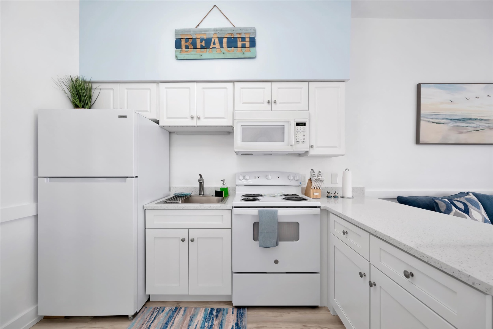 Your fully equipped kitchen features crisp white cabinetry, modern appliances, and cheerful coastal touches—perfect for whipping up meals between beach days.