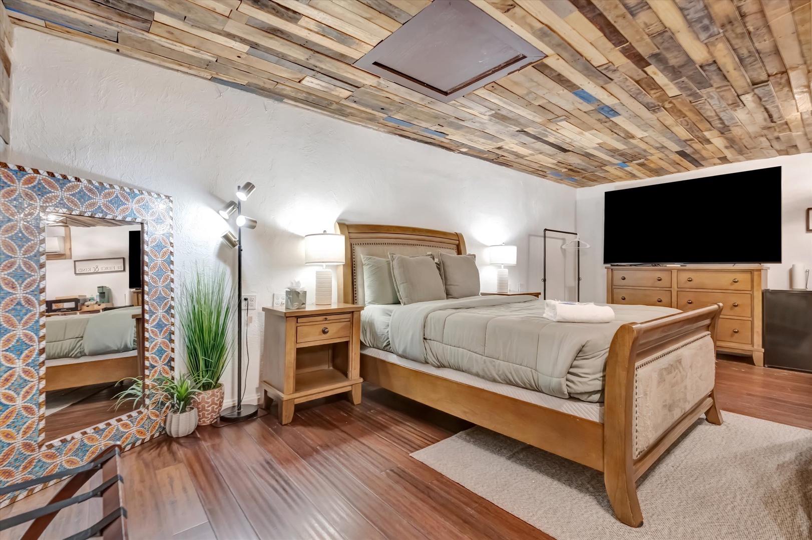 Drift off under a striking reclaimed wood ceiling in this thoughtfully styled bedroom. Your space balances rustic charm with modern comforts—plush bedding, warm wood floors, and gentle lighting for peaceful nights.