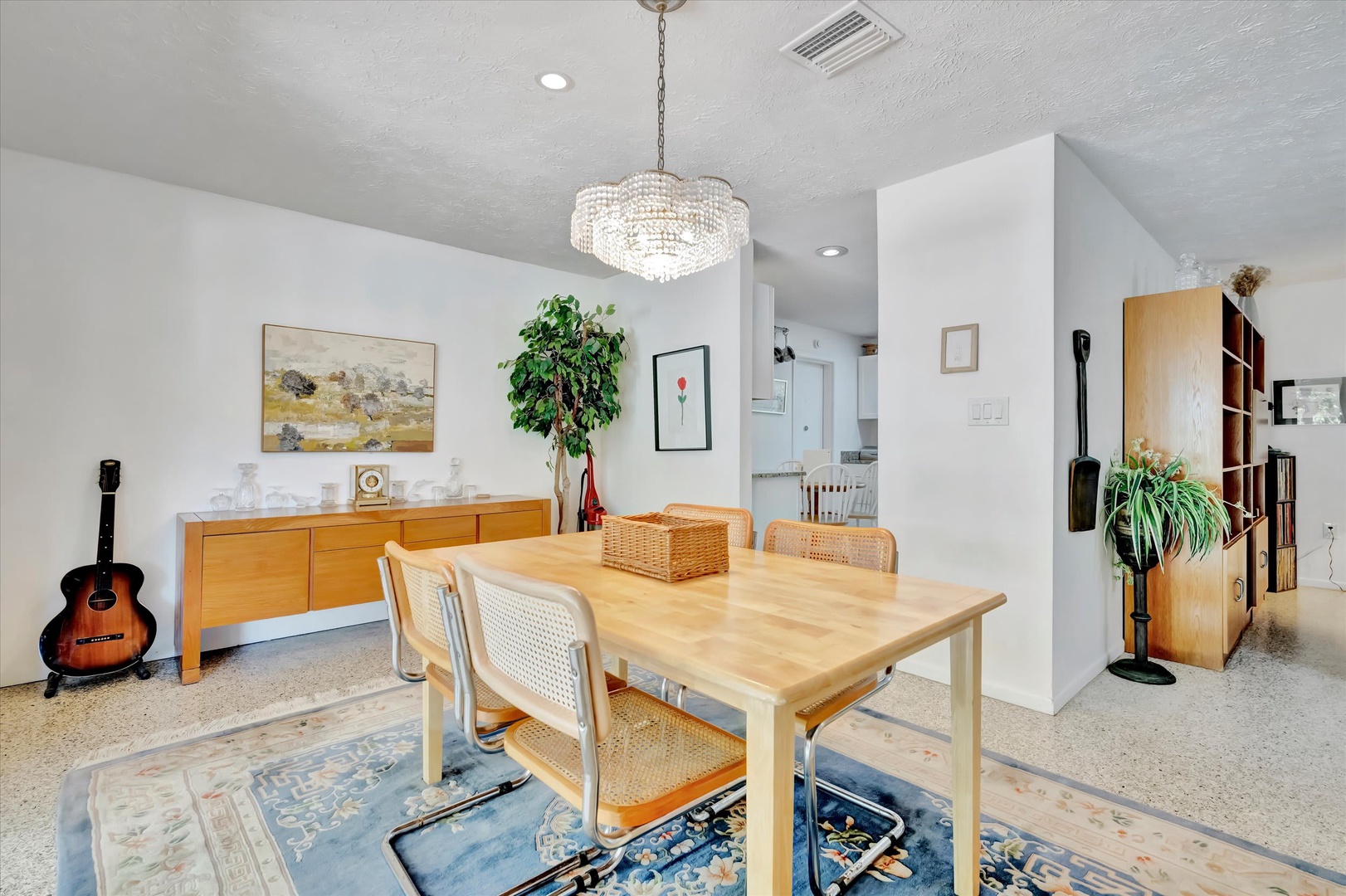Gather around this inviting dining space, where a sparkling chandelier casts a warm glow over your meals. Natural light, elegant wood tones, and thoughtful touches create the perfect spot for your morning coffee or evening conversations.