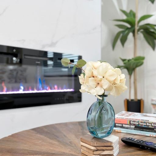 A stylish living space where modern comfort meets elegant design. The sleek fireplace creates a warm focal point, while natural greenery and thoughtful décor invite you to unwind in contemporary ease.