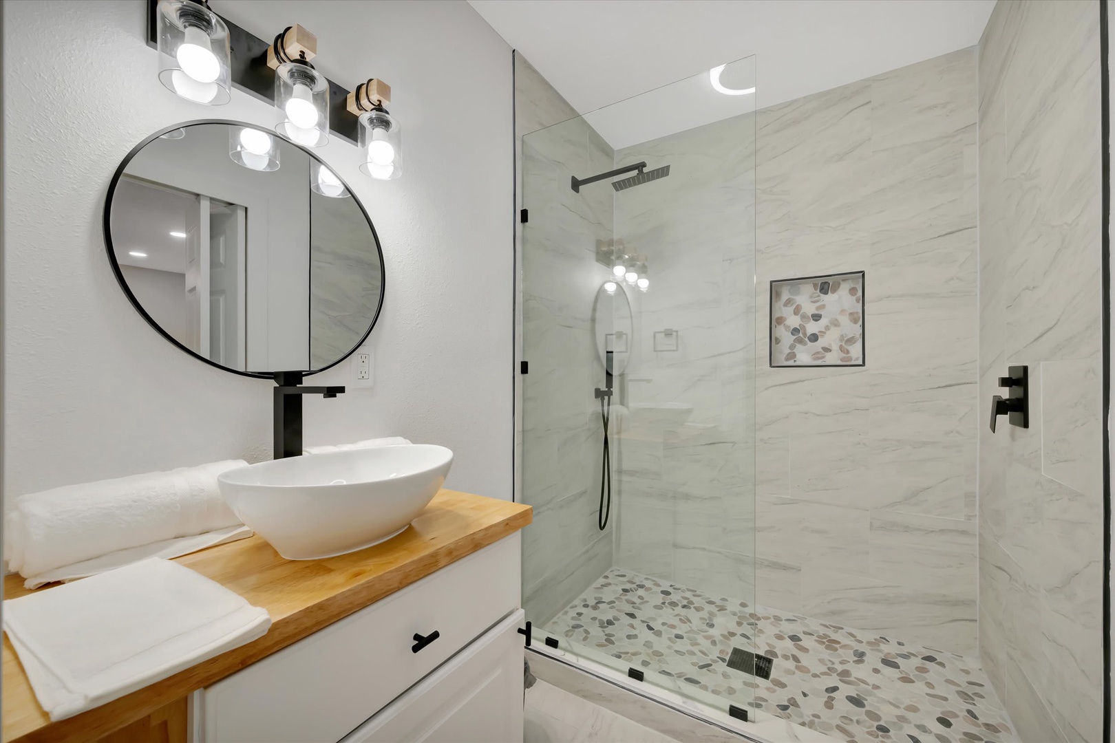 Step into your private spa-like retreat with a sleek walk-in shower, heated rain showerhead, and elegant marble-inspired tile. Fresh towels and a modern vanity await your arrival.