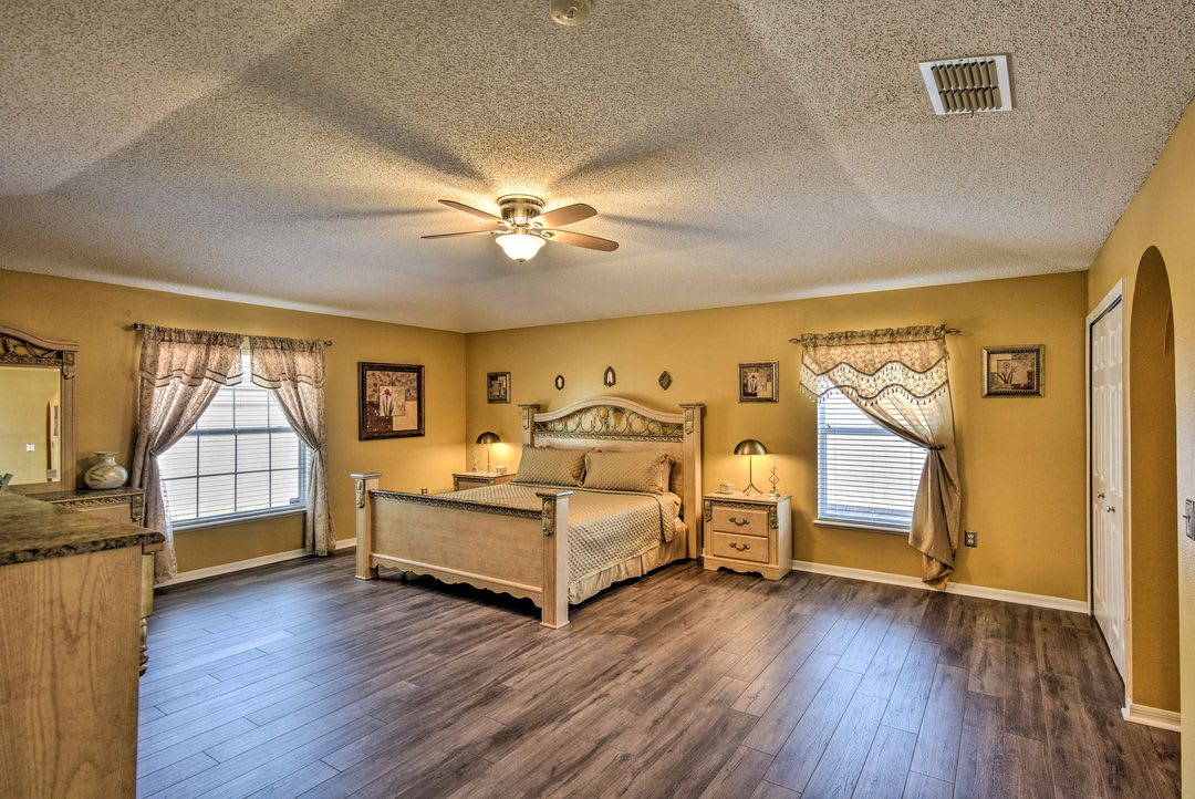 Step into your spacious retreat with warm golden walls, rich hardwood floors, and a welcoming bed ready for restful nights. Natural light fills the room while a gentle ceiling fan keeps the air fresh and comfortable.