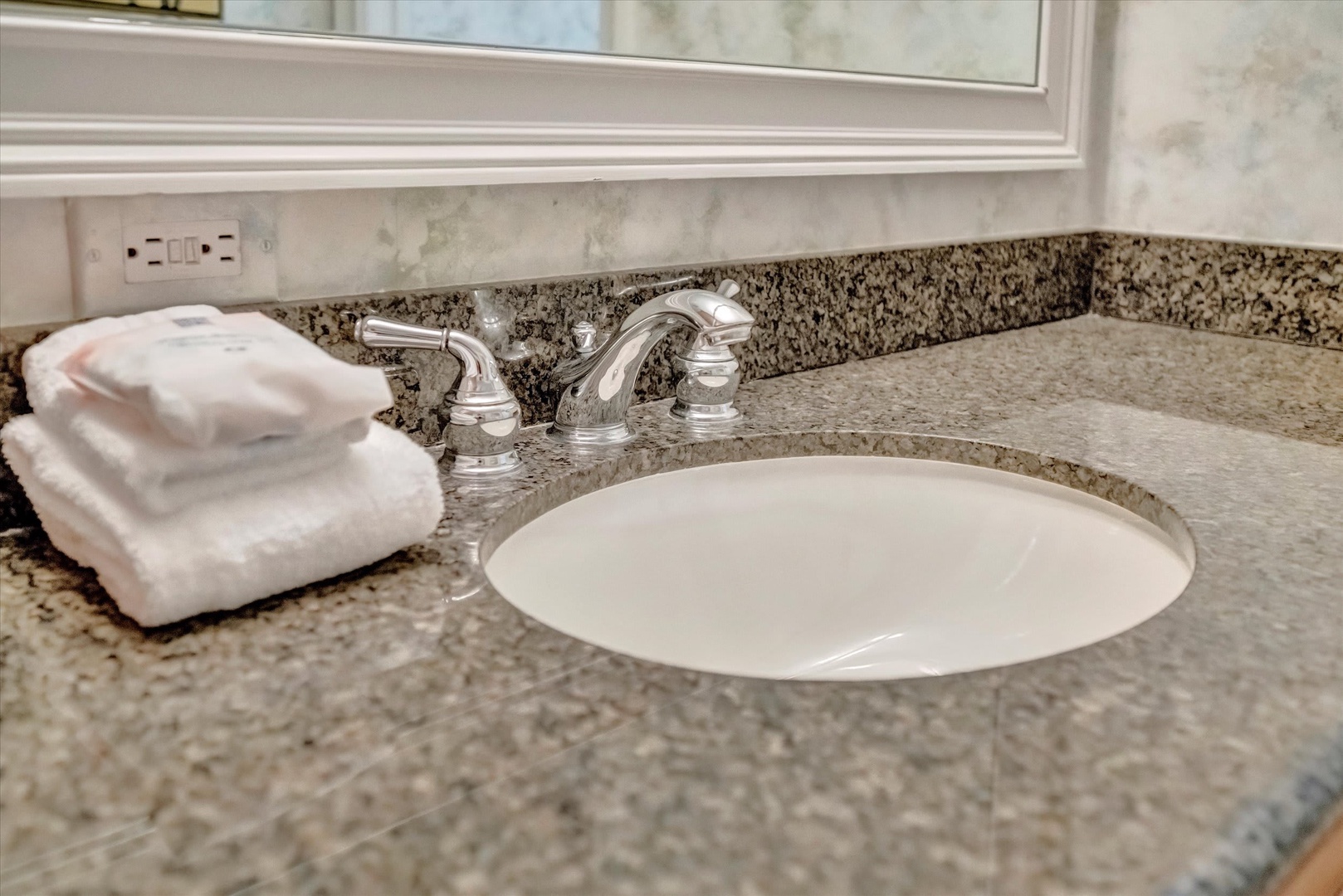 Step into a bathroom designed with your comfort in mind, where polished granite countertops, a gleaming sink, and freshly folded towels await your arrival.