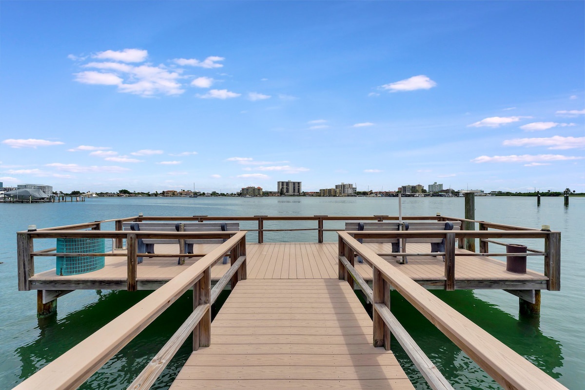 A private dock extends over turquoise waters, with built-in benches and a waterside cityscape beyond. Perfect for morning coffee or watching boats pass by.