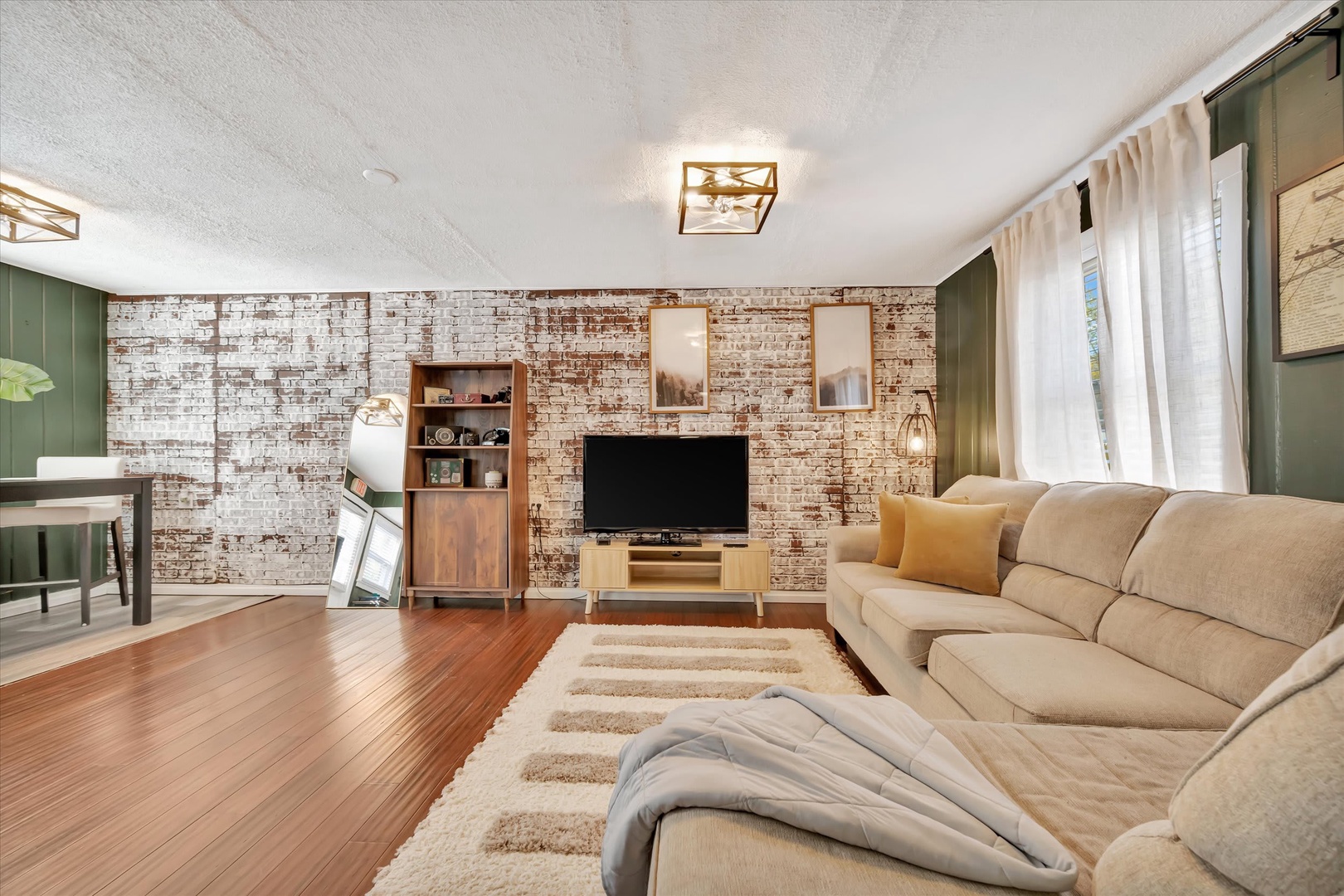 Sink into the plush sofa and unwind in your spacious living room, where warm wood floors and exposed brick create a cozy, inviting atmosphere perfect for relaxing after a day of exploring.