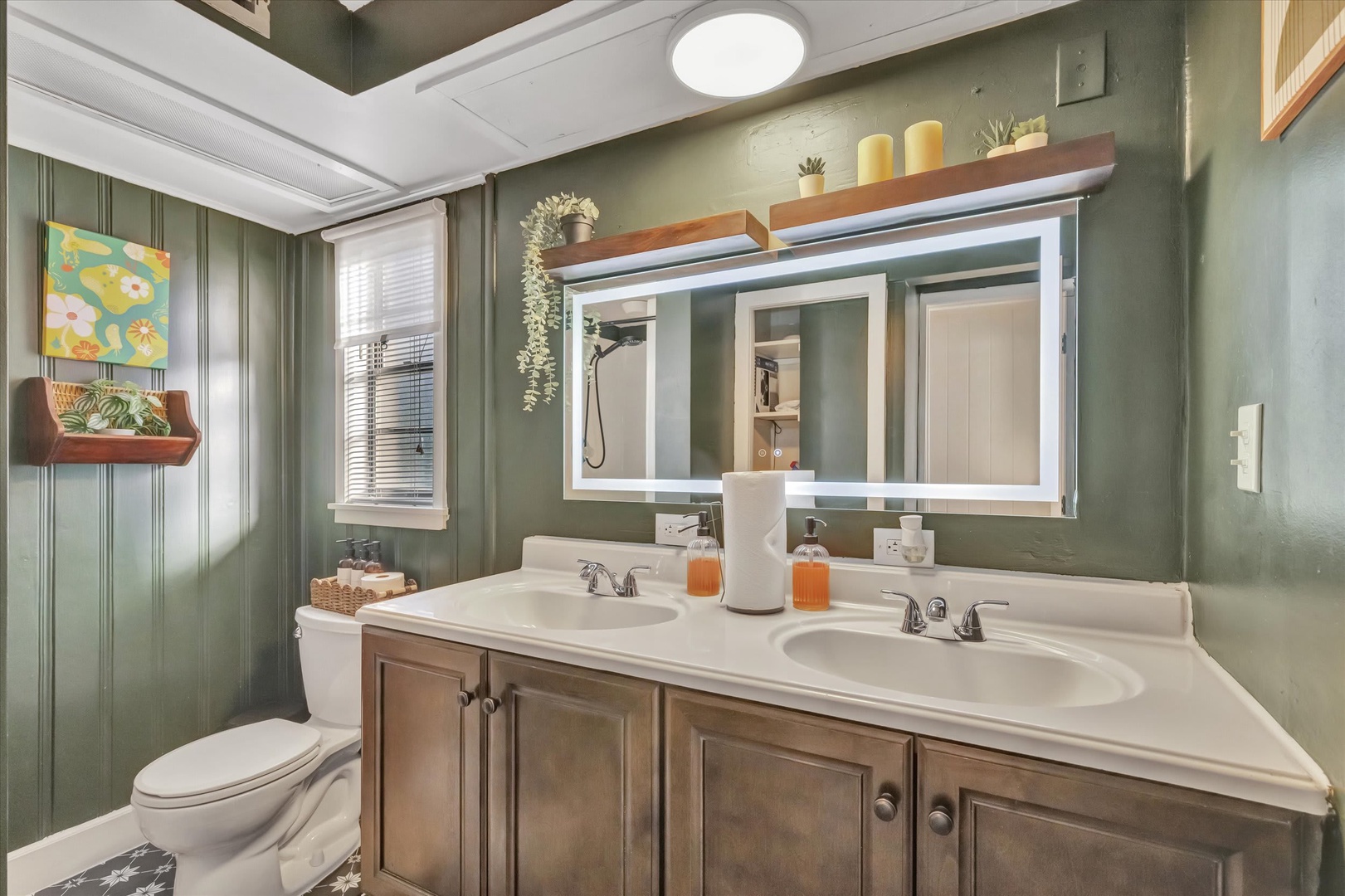 Step into this stylish bathroom where rich green tones and natural light create a calming retreat. Twin sinks and thoughtful décor make your morning routine feel like a spa moment.