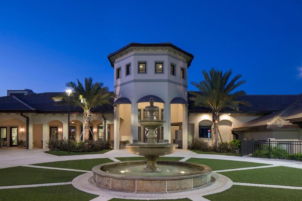 An elegant Mediterranean-style property features a distinctive tower entrance flanked by palm trees, with a grand tiered fountain creating a welcoming focal point at the front of the home.