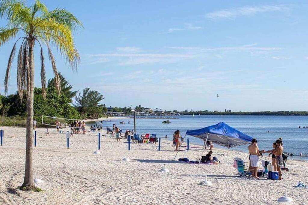 A pristine sandy beach with calm blue waters stretches along the shoreline, where palm trees and volleyball nets invite you to soak up the sun and enjoy endless coastal recreation.