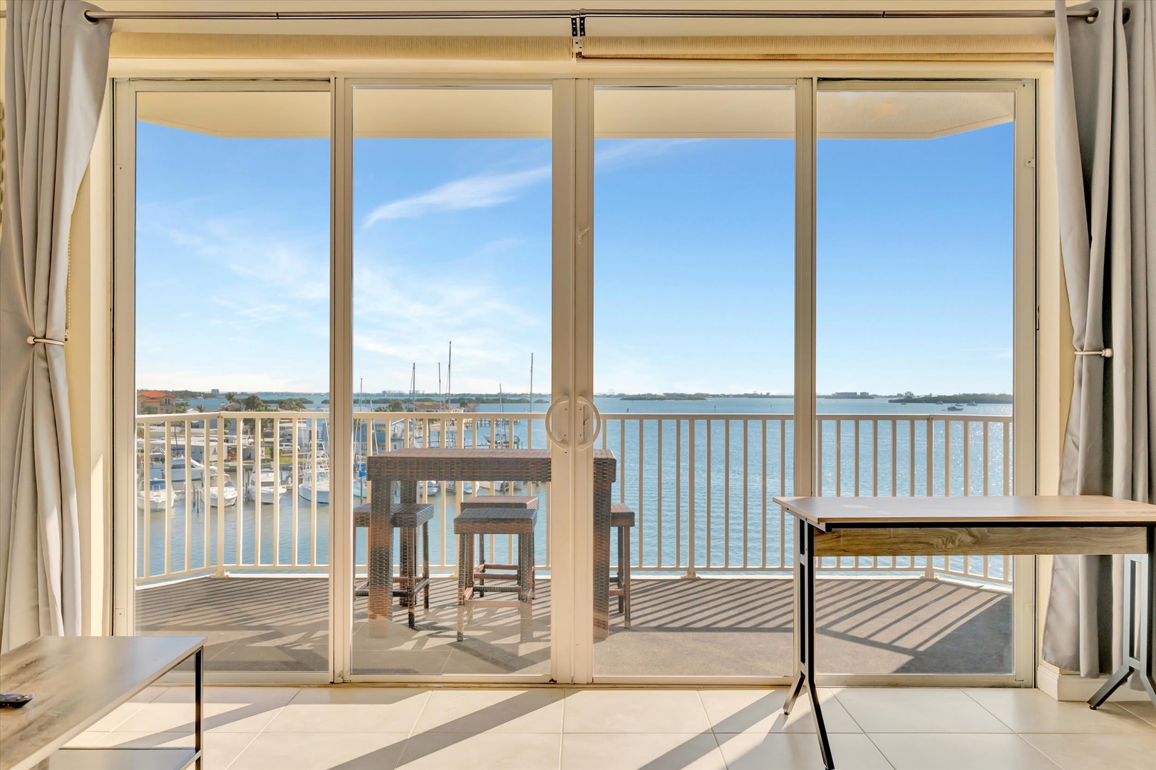 Step through sliding glass doors to your private waterfront terrace, where tranquil bay views stretch to the horizon and wicker seating invites you to linger over morning coffee or sunset reflections.