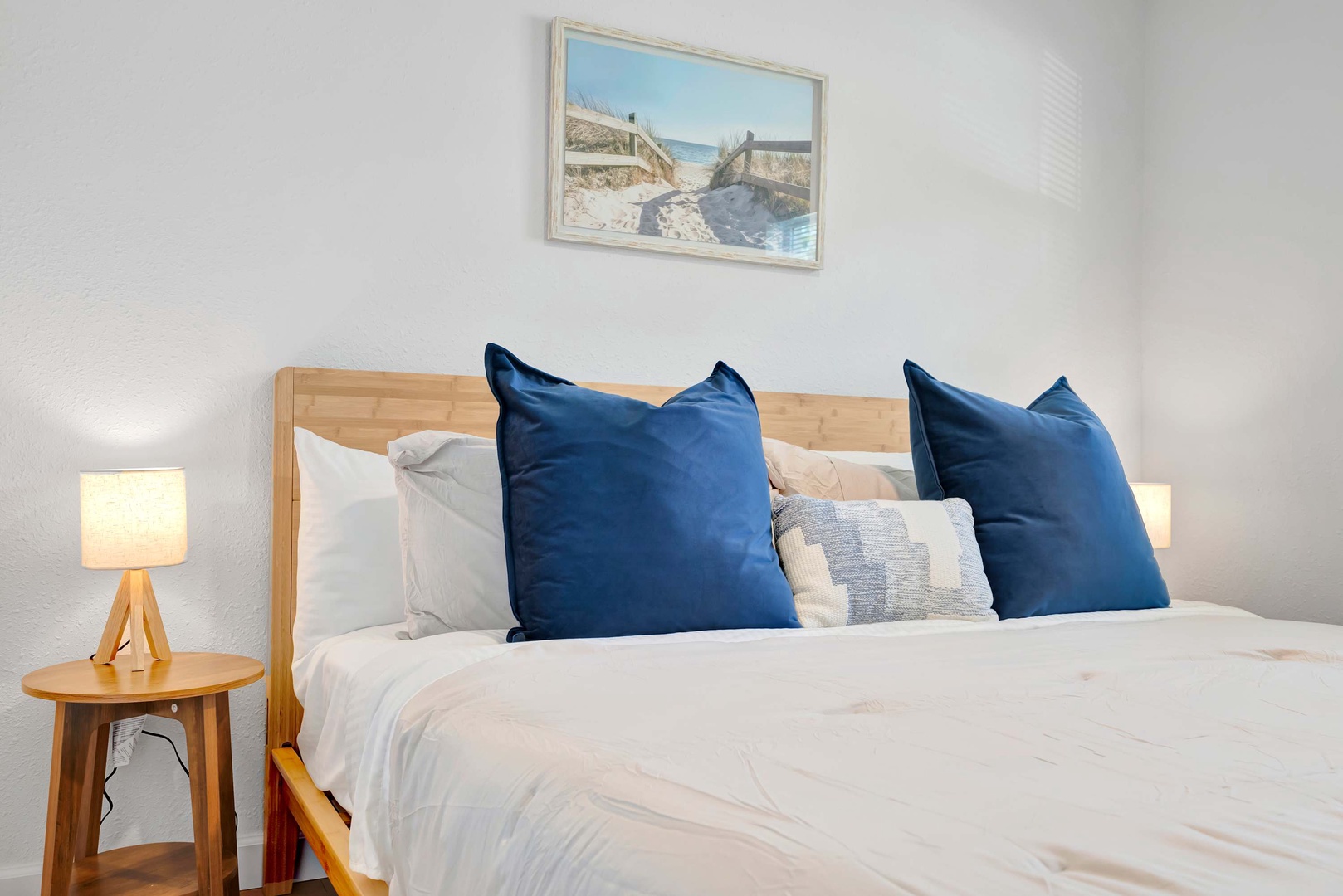 Sink into crisp white linens and plump navy pillows after a day of exploring. Your cozy retreat features warm wood tones and soft lighting for a peaceful night's rest.
