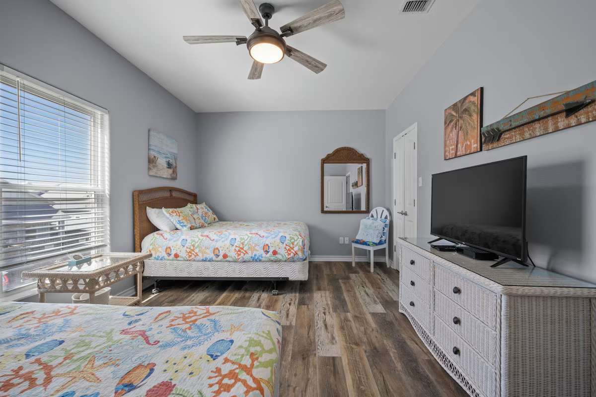 Bright coastal bedroom with cheerful bedding and gentle ceiling fan breeze to keep you comfortable after beach days.