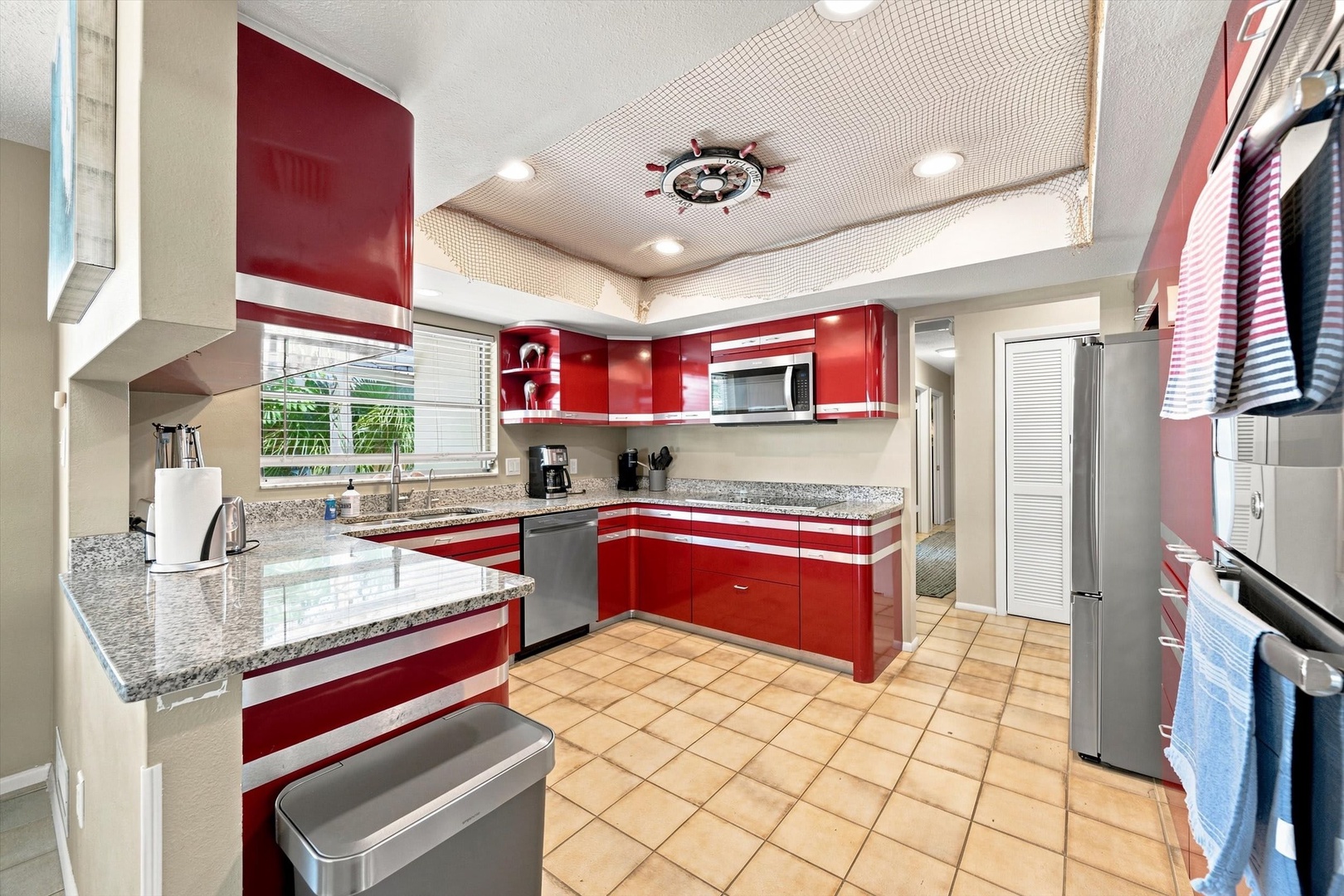 Your fully-equipped kitchen awaits with bold red cabinetry, granite countertops, and stainless appliances—perfect for preparing your favorite meals in a space that's both stylish and functional.